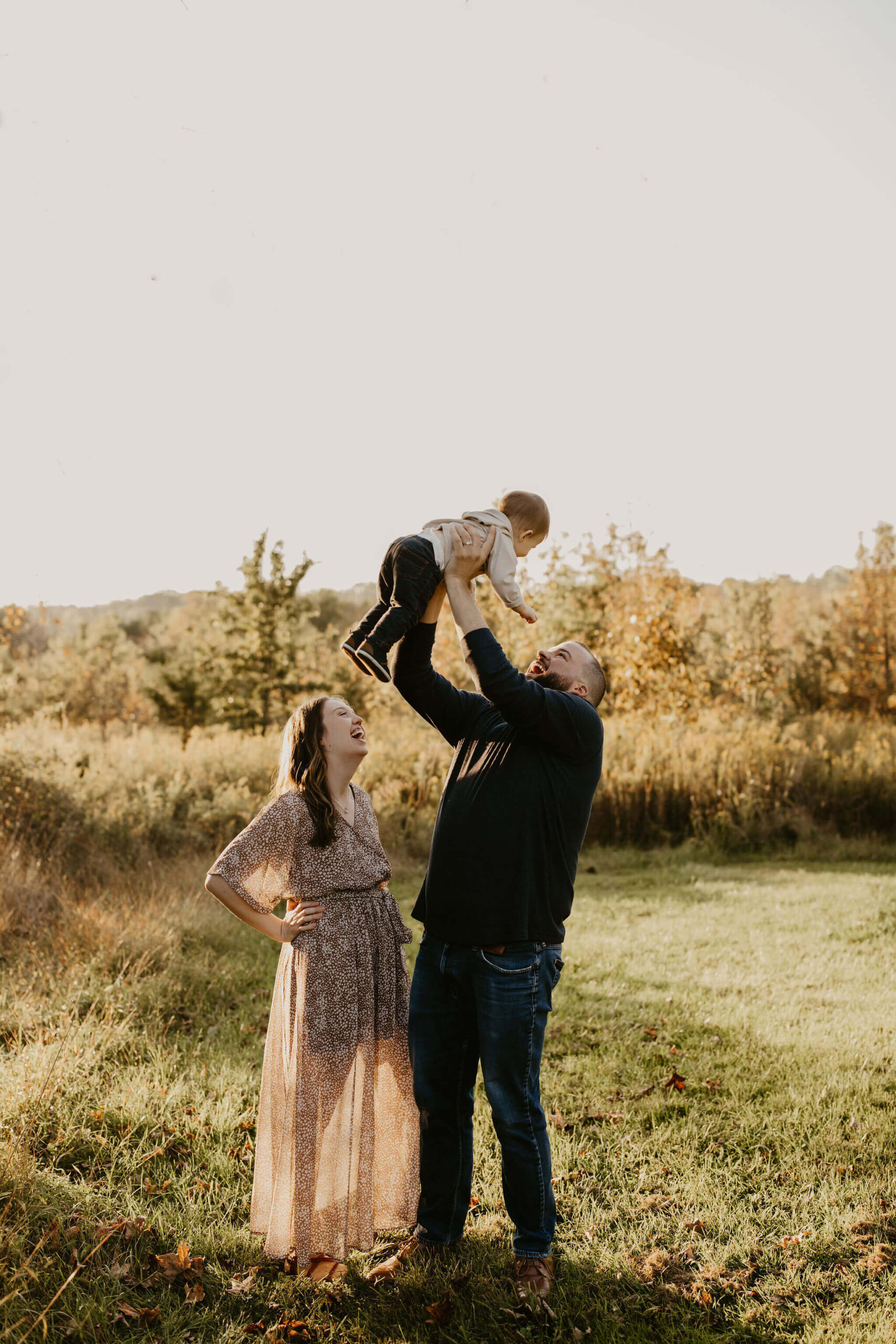 a father throwing his young son in the air while the mother watches, all laughing