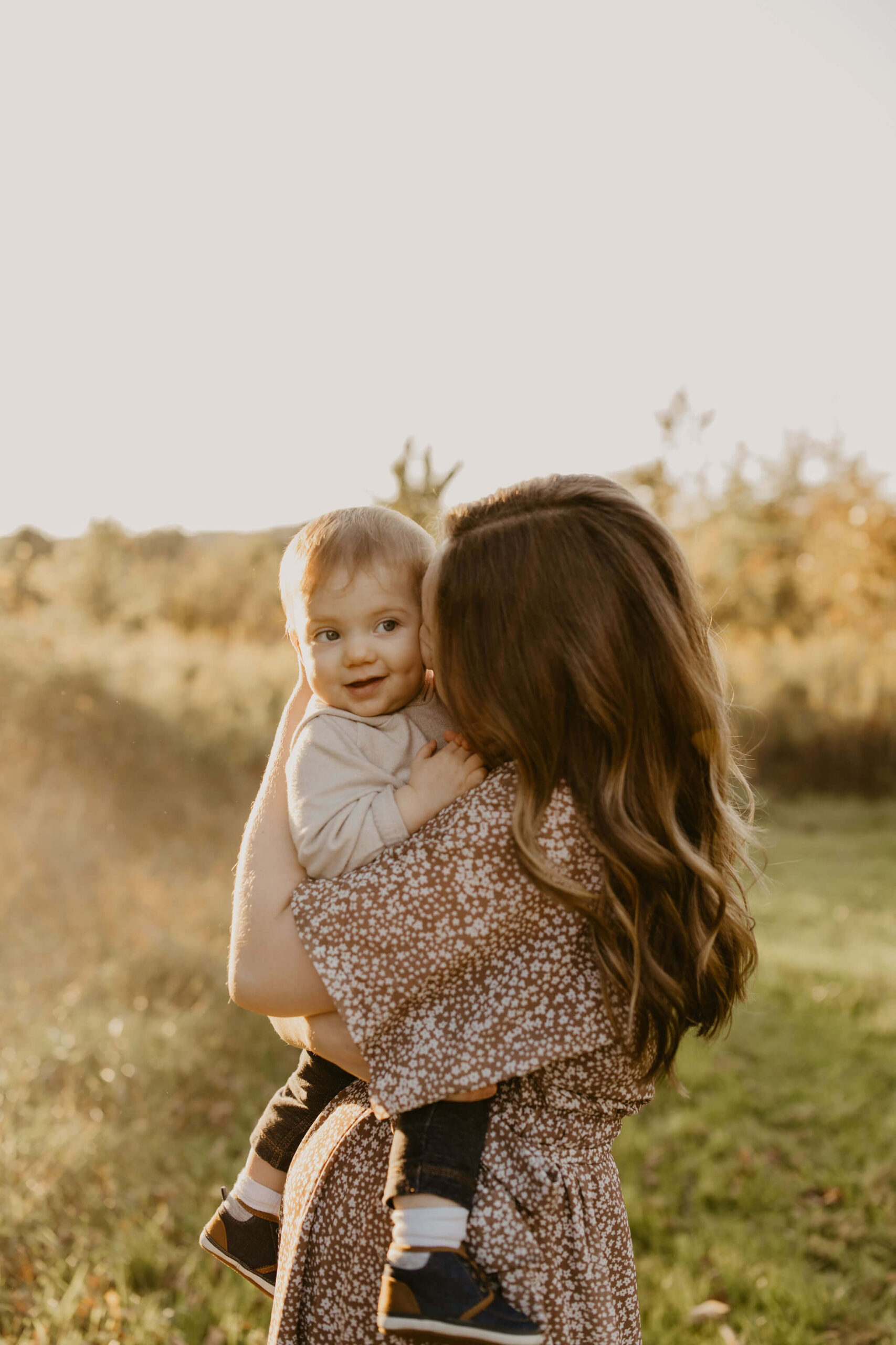 a mother cuddling up to her son outside in a field