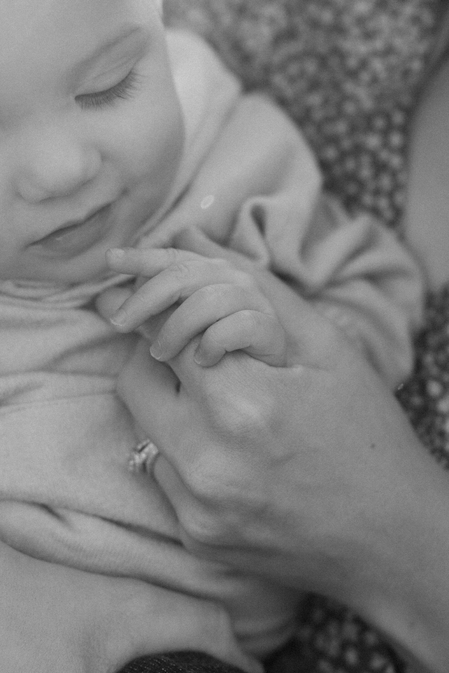 close up black and white image of a mother holding her son's hand