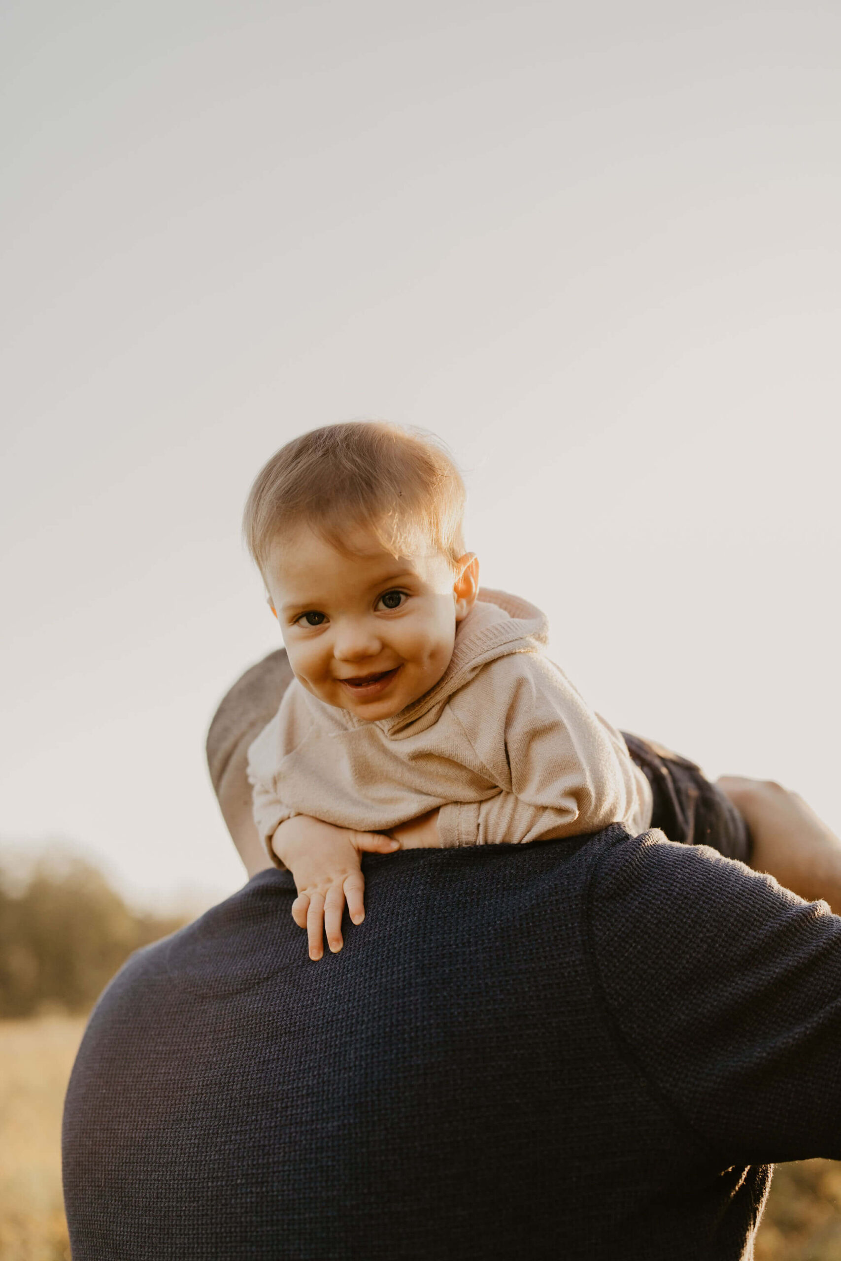 a dad throwing his son over his shoulder, who is laughing toward the camera