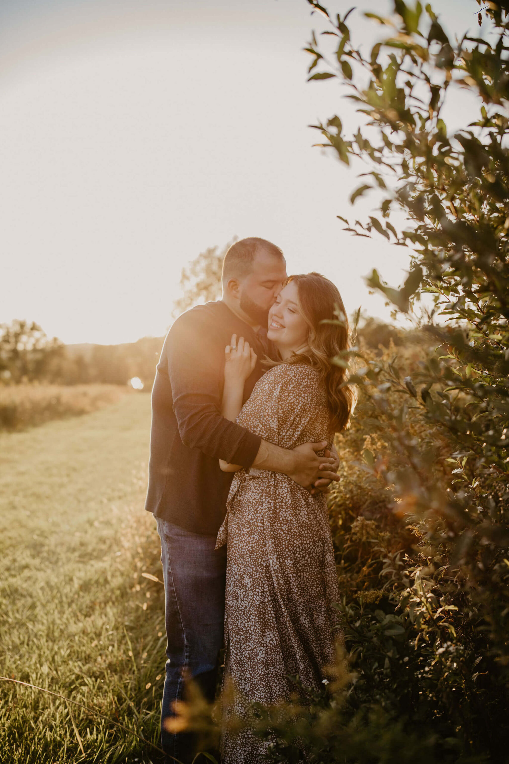 a husband and wife embracing during sunset in a beautiful golden field