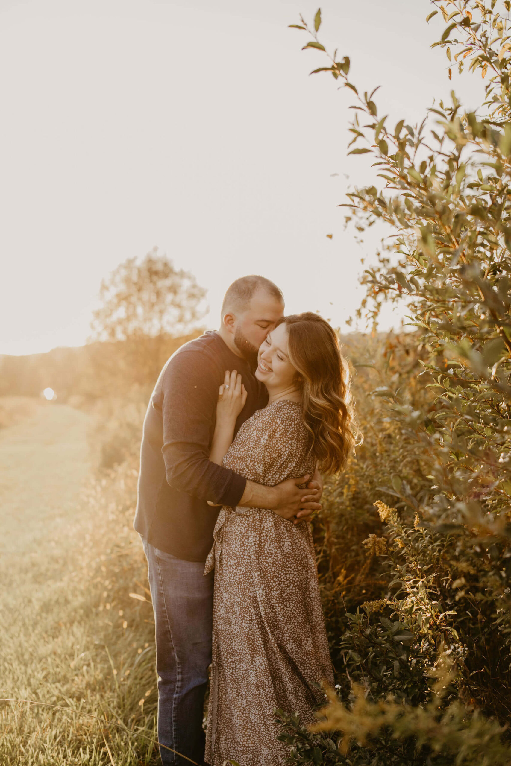 a husband kissing his wife on the cheek during golden hour