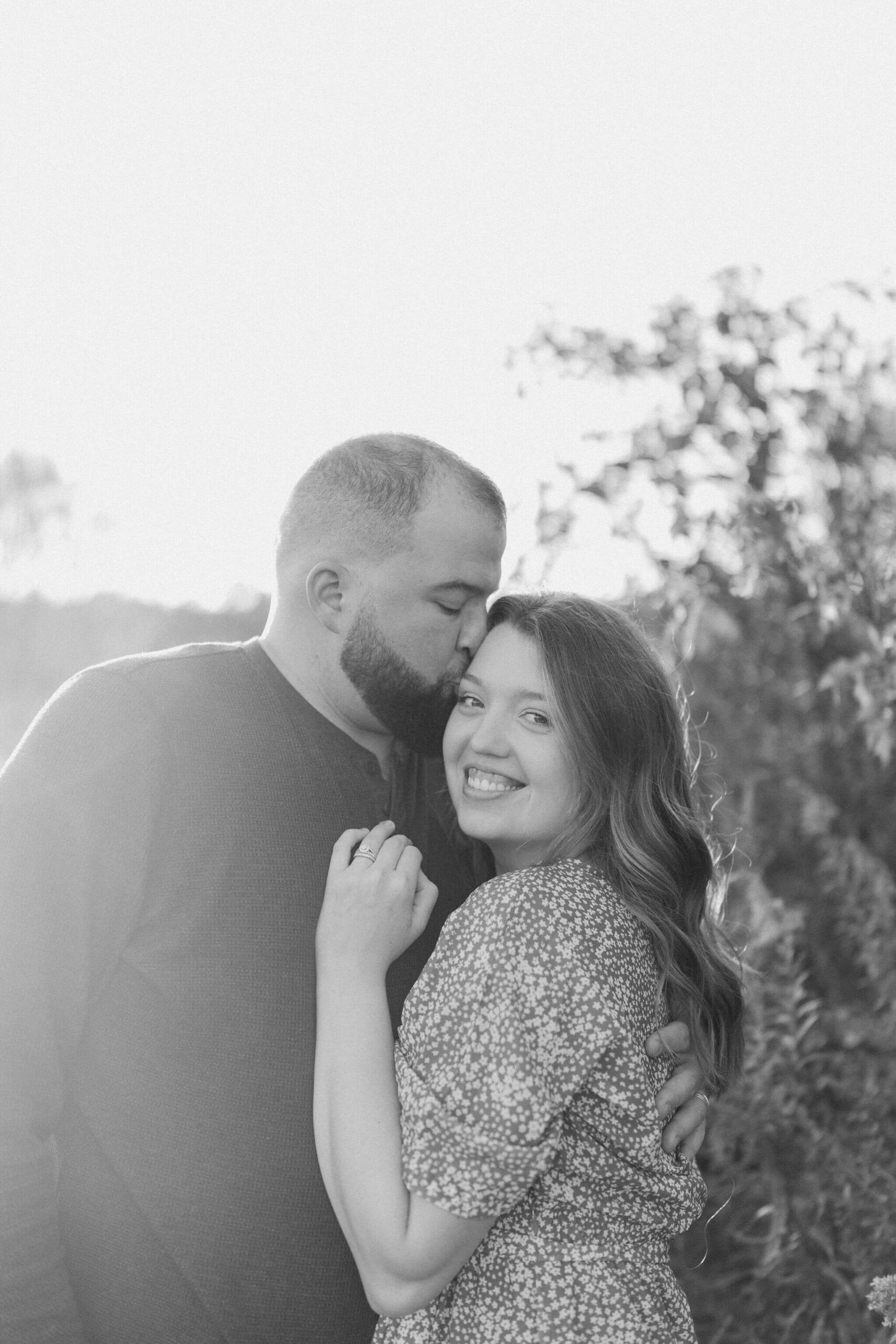 black and white image of a man kissing his wife on the cheek