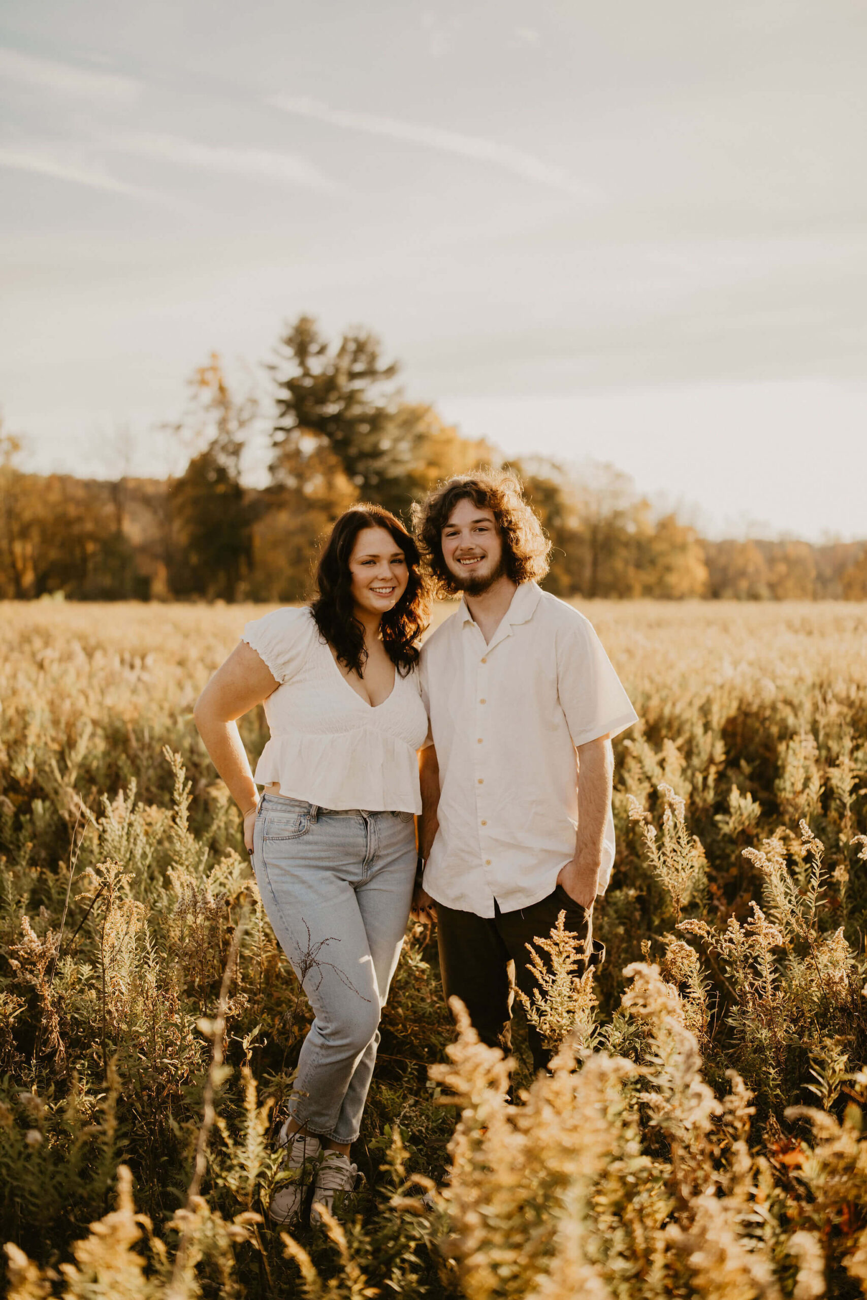 a boy and a girl posing for a photograph in a field