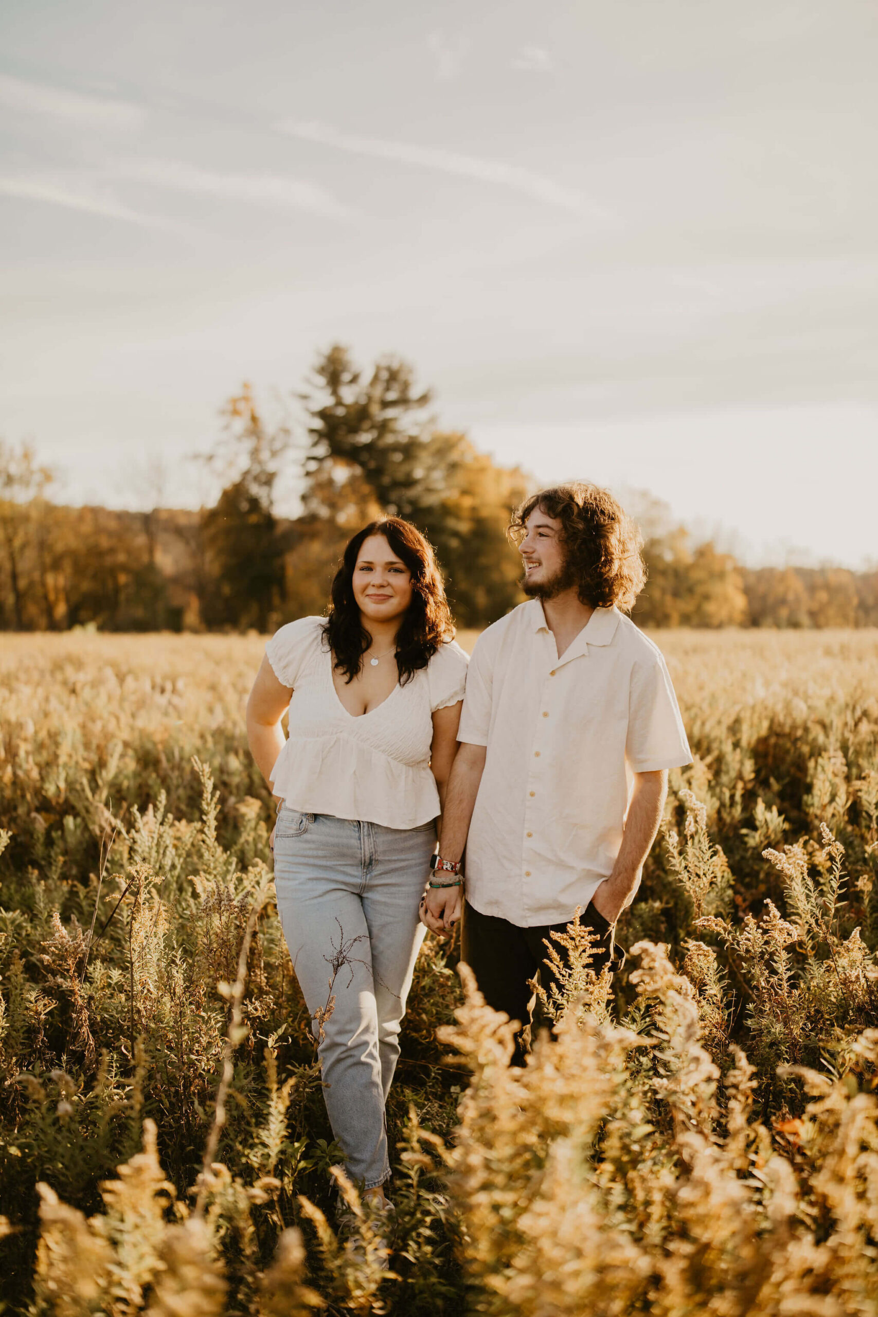 a boy and a girl posing for a photograph. he is looking off camera, she is smiling softly at the camera