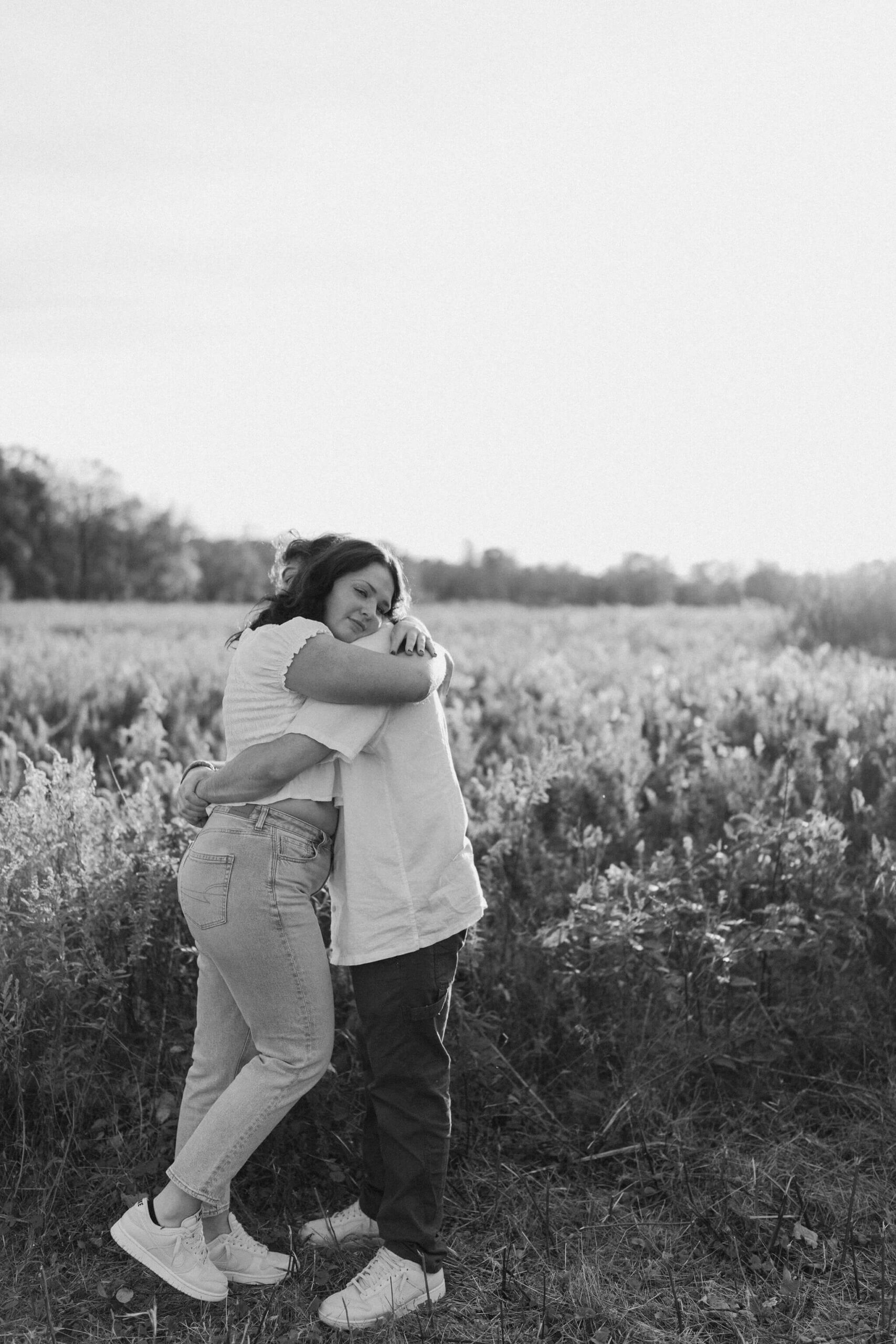 black and white image of a boy and a girl embracing. she is smiling softly at the camera