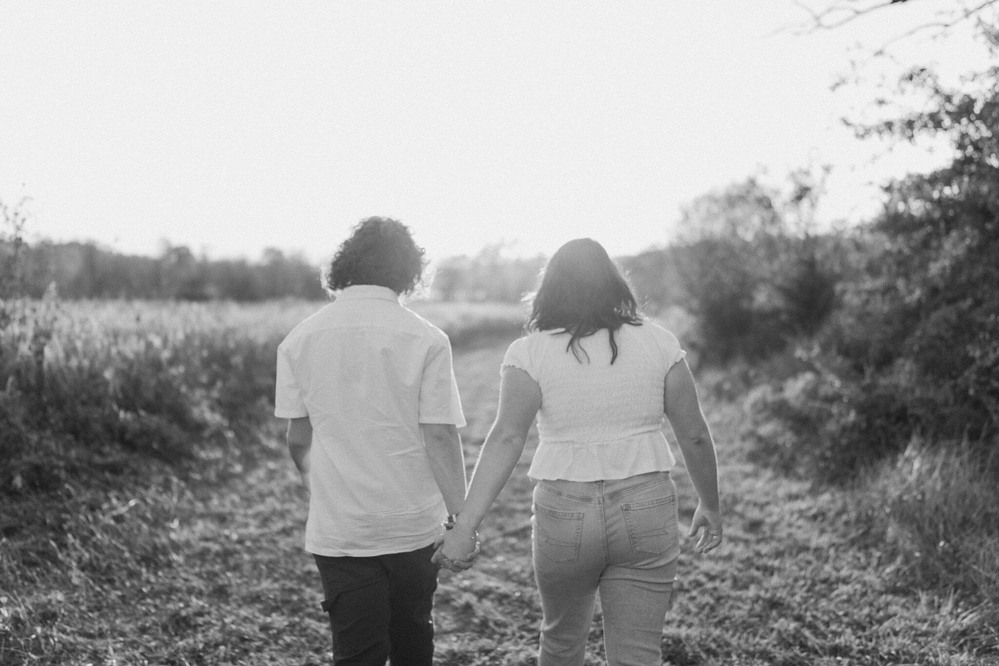 black and white, grainy image of a boy and a girl walking toward the sunset away from the camera