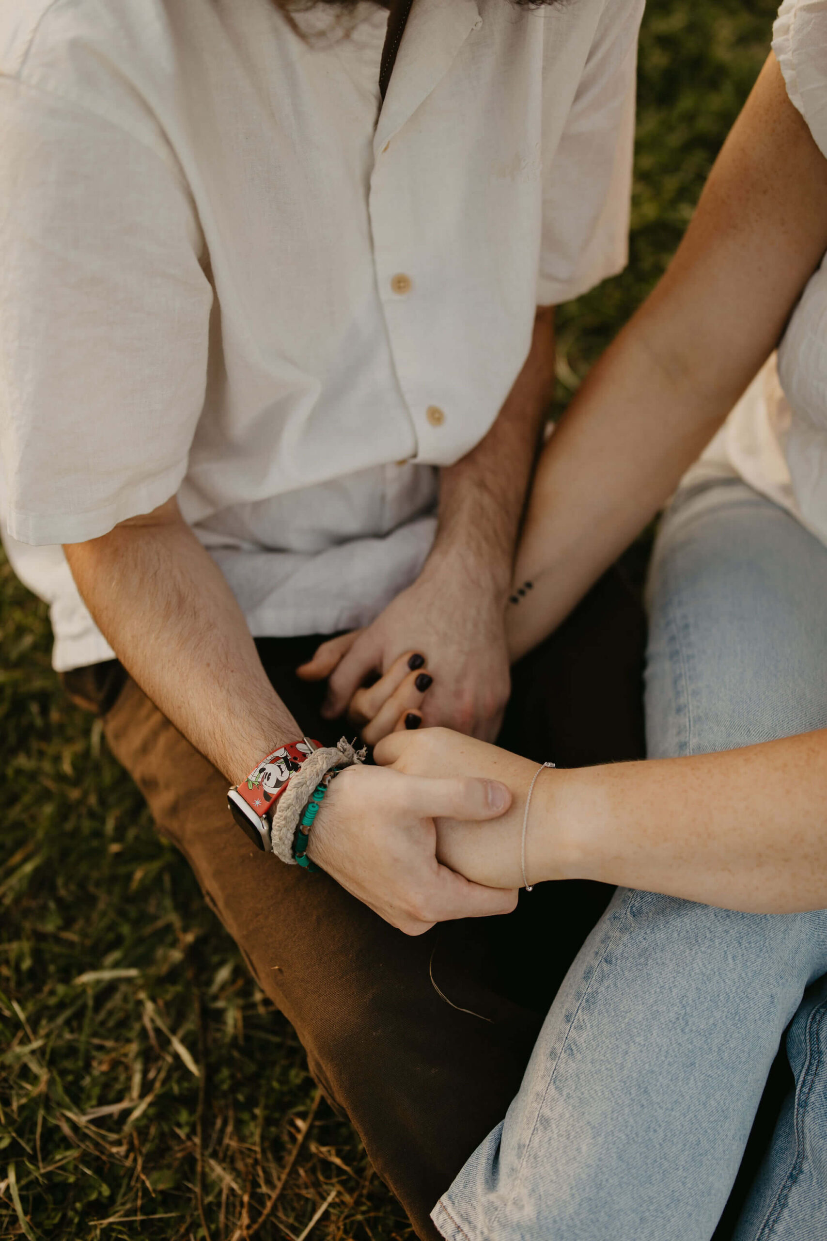 close up image of a couple seated on the ground holding hands