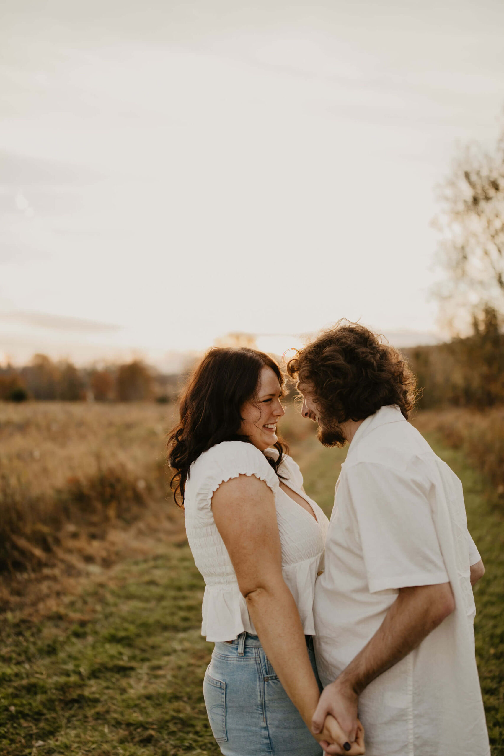 a boy and a girl holding hands in a field and smiling at each other