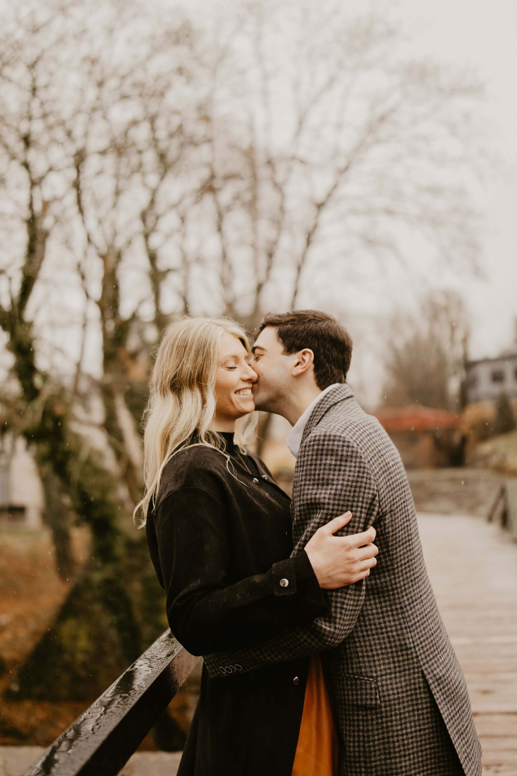 man kissing a woman on the cheek on a walking bridge, both smiling