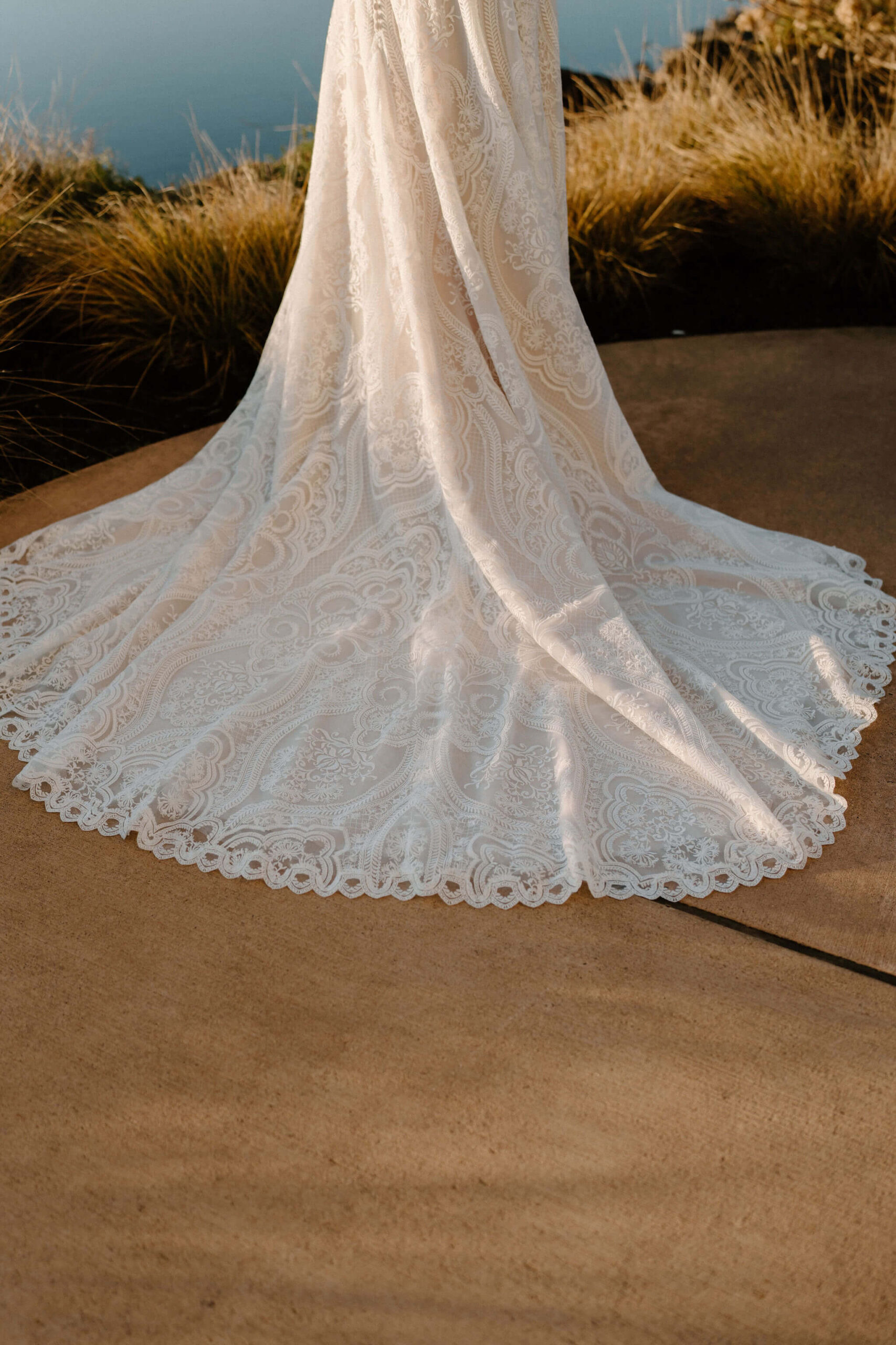 close up image of bride's off-white, textured wedding dress spread out behind her