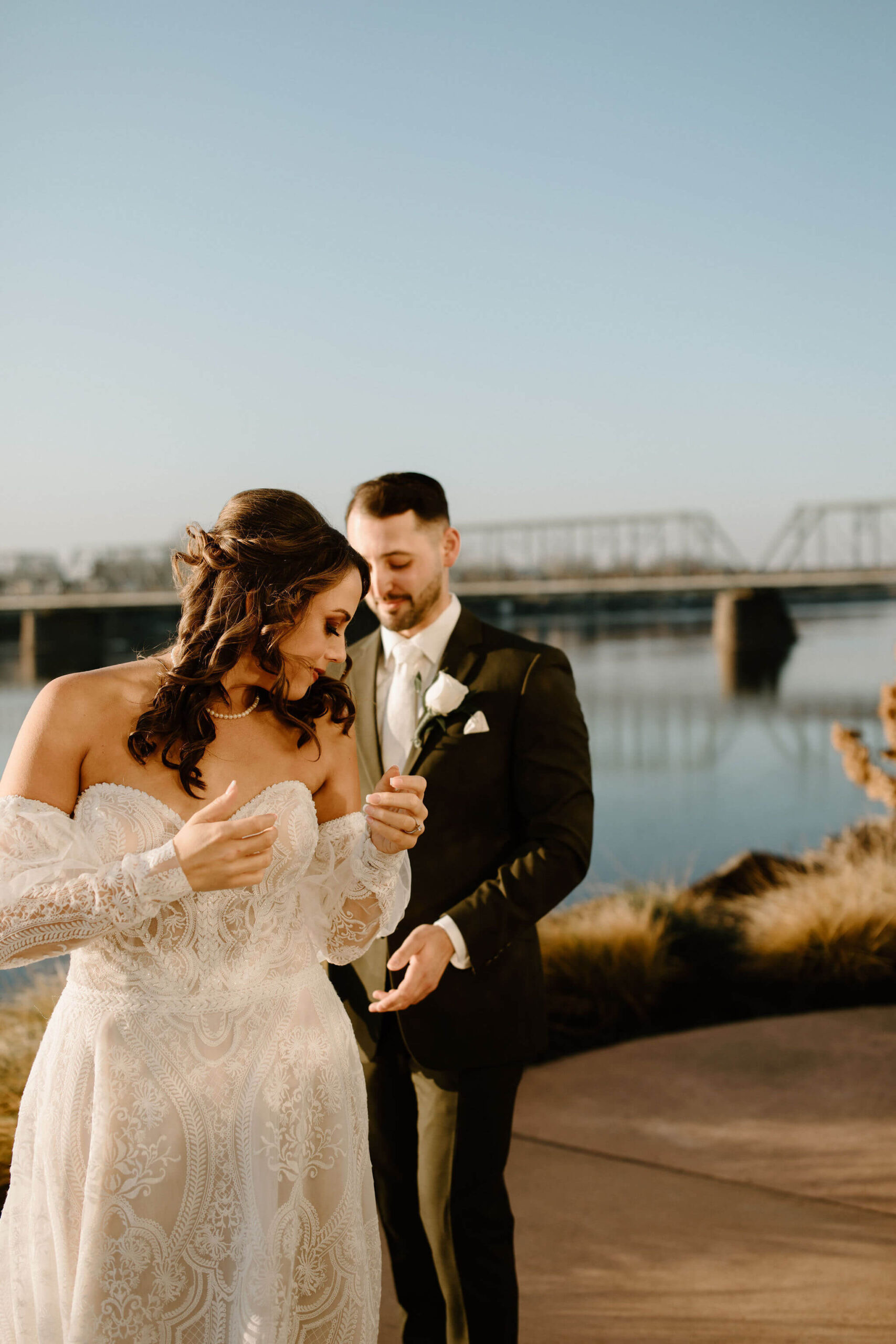 groom (brown hair, green suit) seeing his bride's (brown hair, textured off-white dress) wedding dress for the first time.