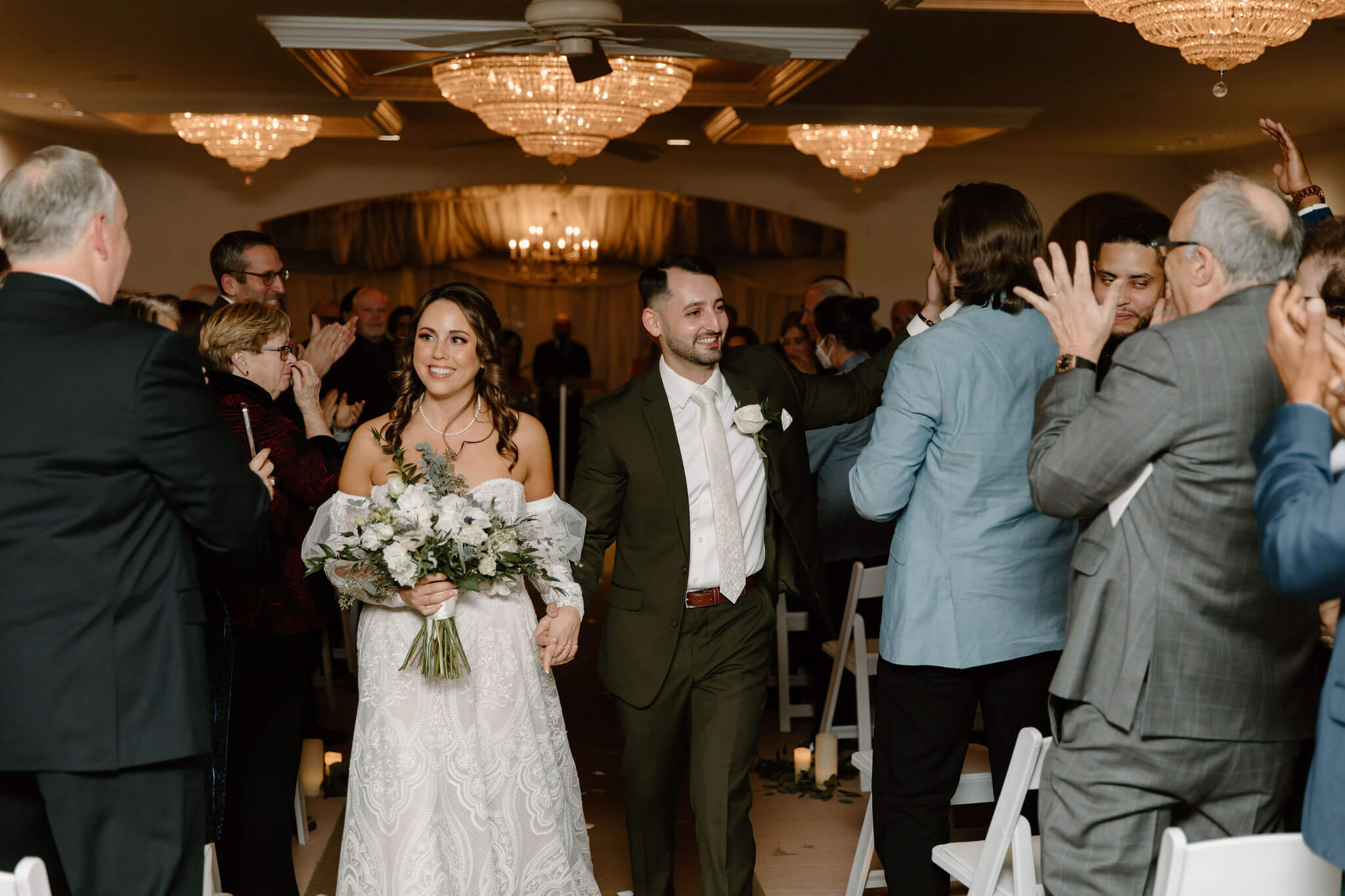 bride and groom walking up the aisle in their wedding recessional, smiling at their guests