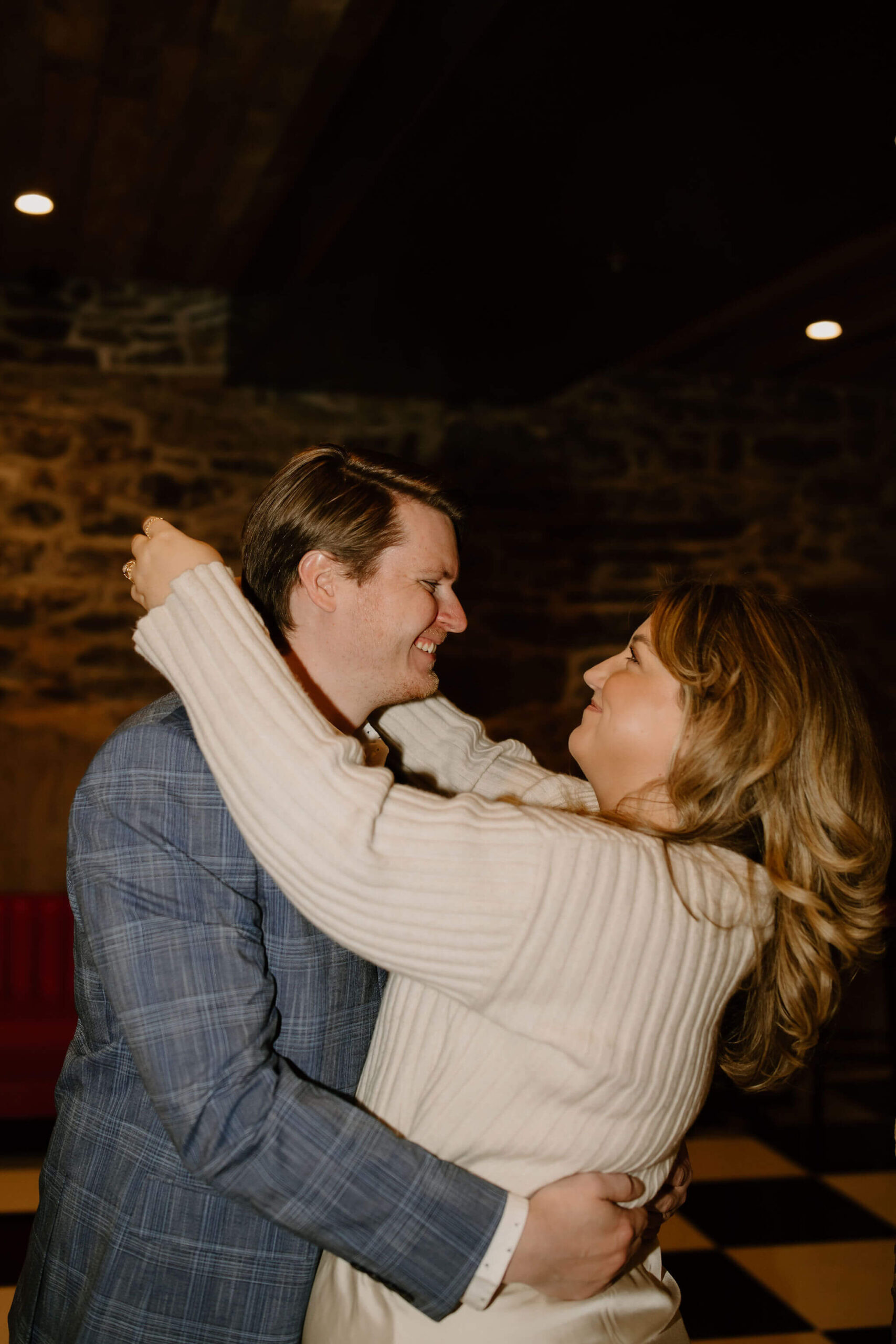 a couple embracing, with her arms around his neck, smiling at each other