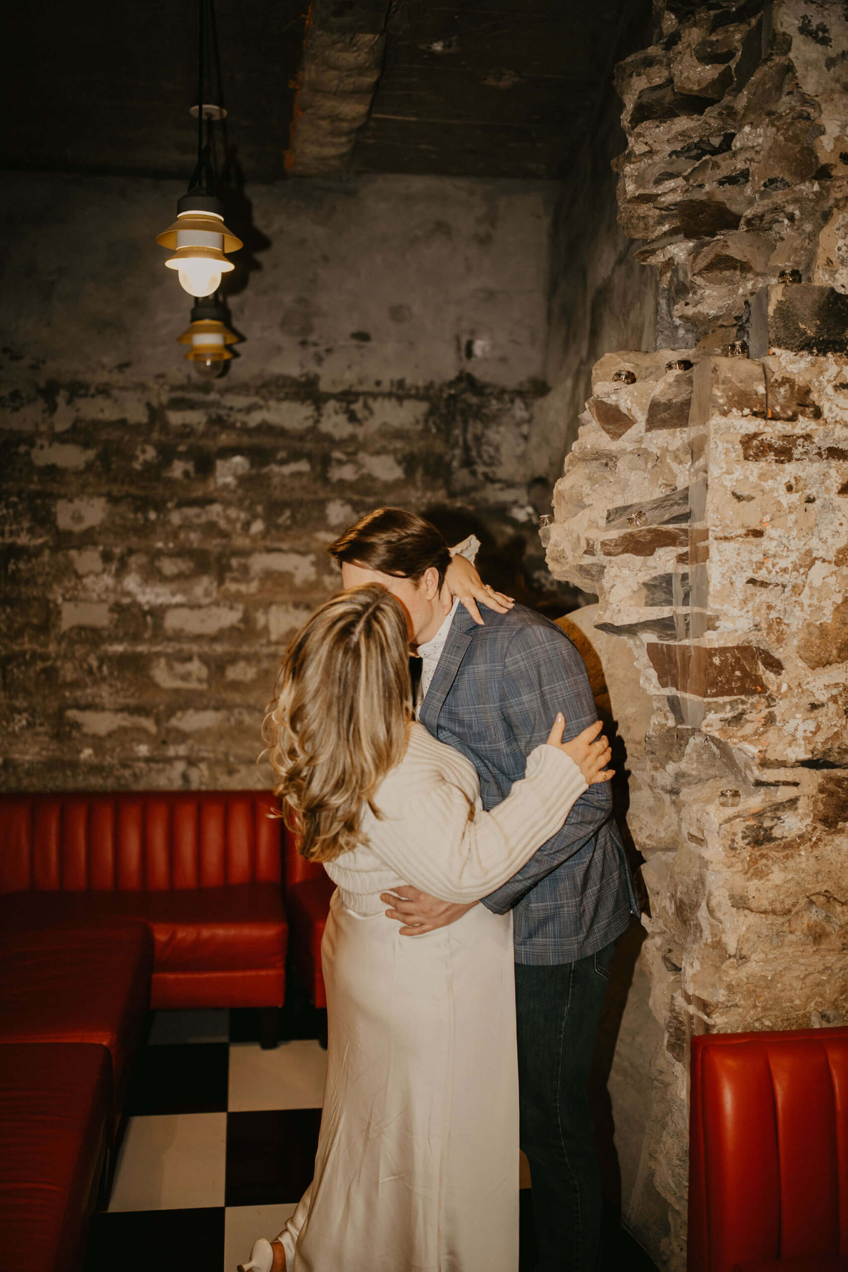 a couple kissing, with her arms around his neck and his arms around her waist. 