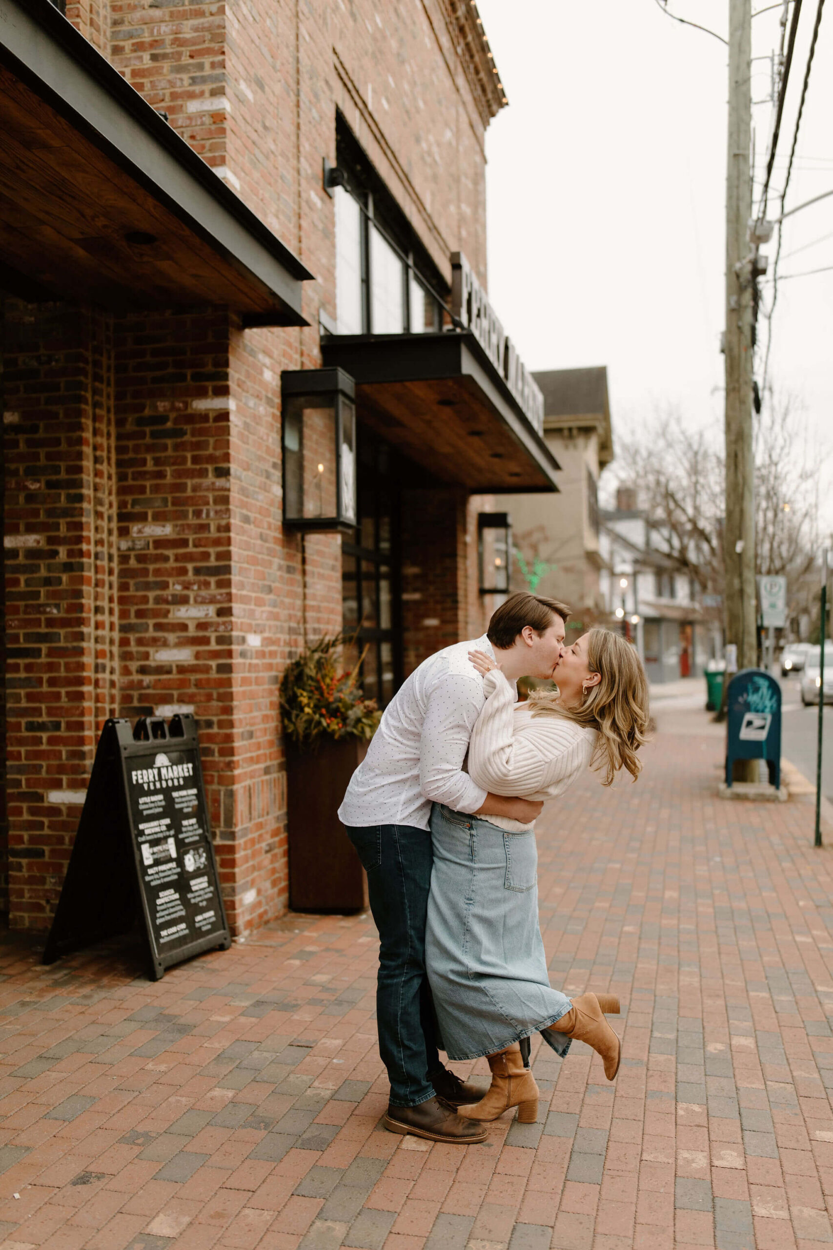 a man kissing his fiance, arms wrapped around her waist and bending her back while she holds his shoulders