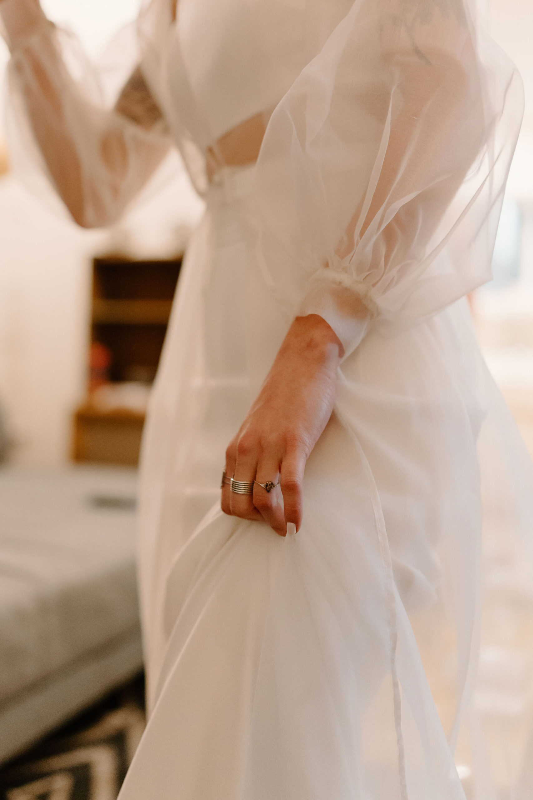 close up image of a bride's hand holding up her skirt, focusing on her salt and pepper diamond engagement ring