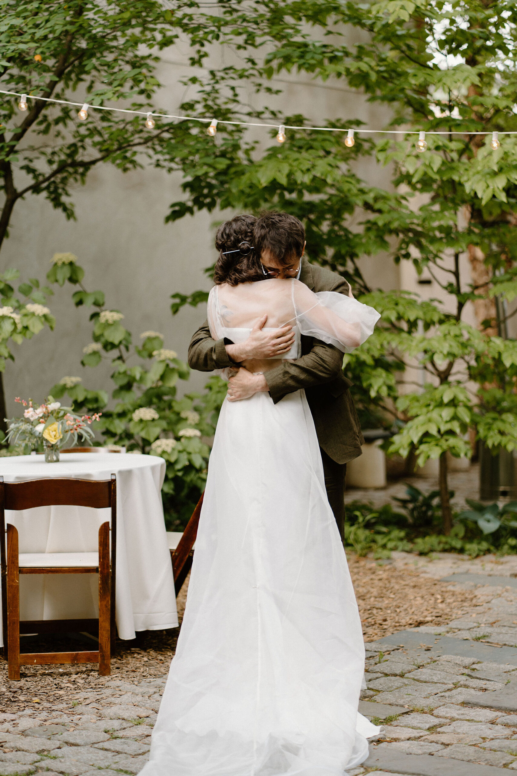 bride and groom embracing after their wedding ceremony, away from their guests, in a lush green cobblestone courtyard