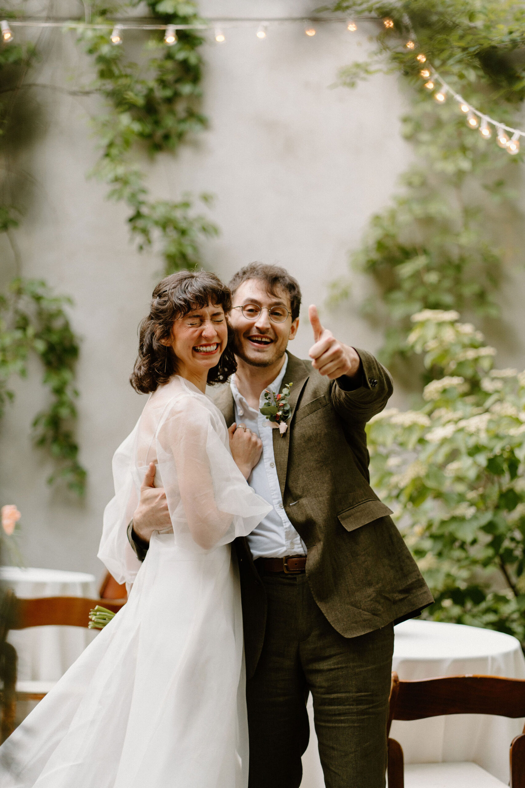 bride and groom smiling at the camera while groom gives a thumbs up after their wedding ceremony