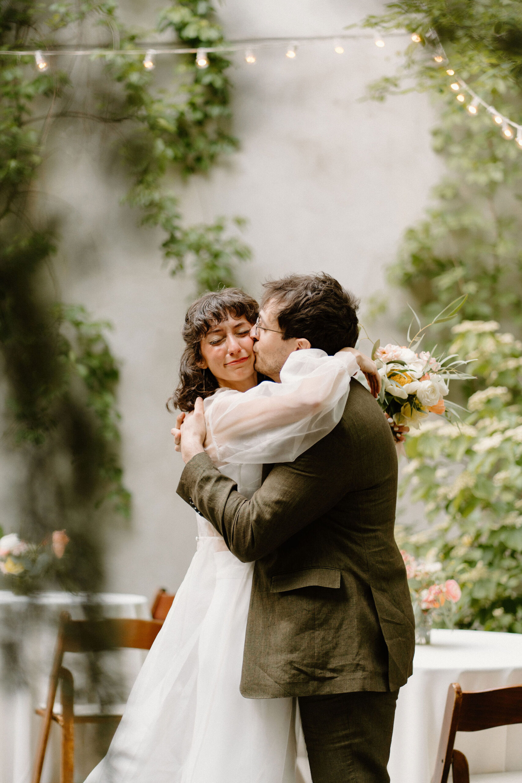 groom kissing bride on the cheek as she cries after their wedding ceremony 