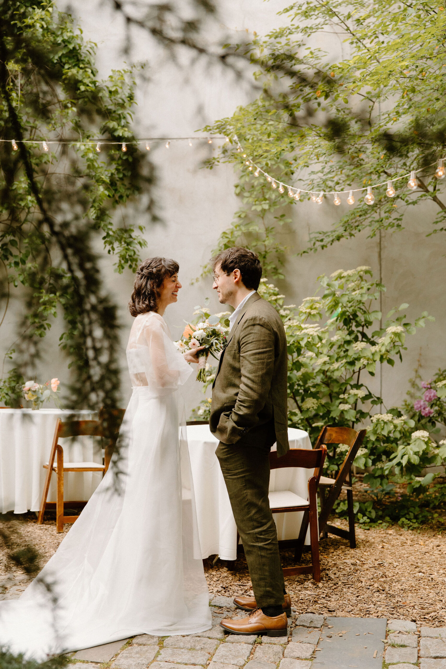 bride and groom taking a private moment to talk after their ceremony in the cocktail hour space, within a lush green cobblestone courtyard