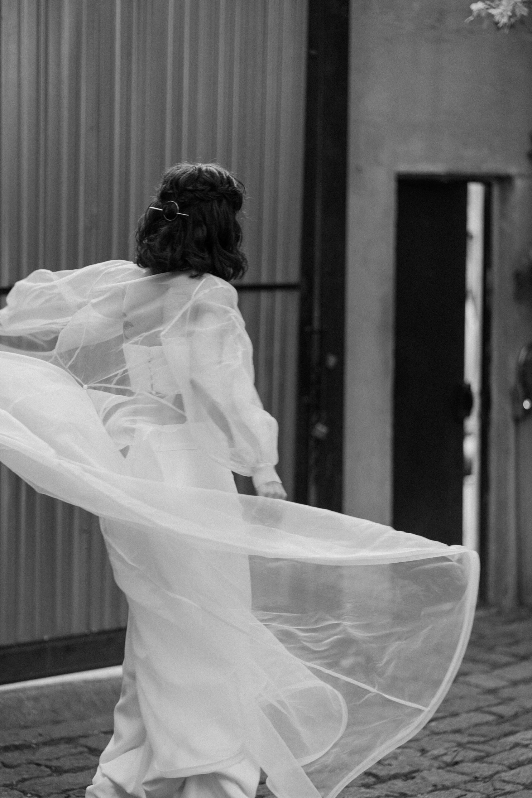 black and white, blurry image of a bride twirling her cape 