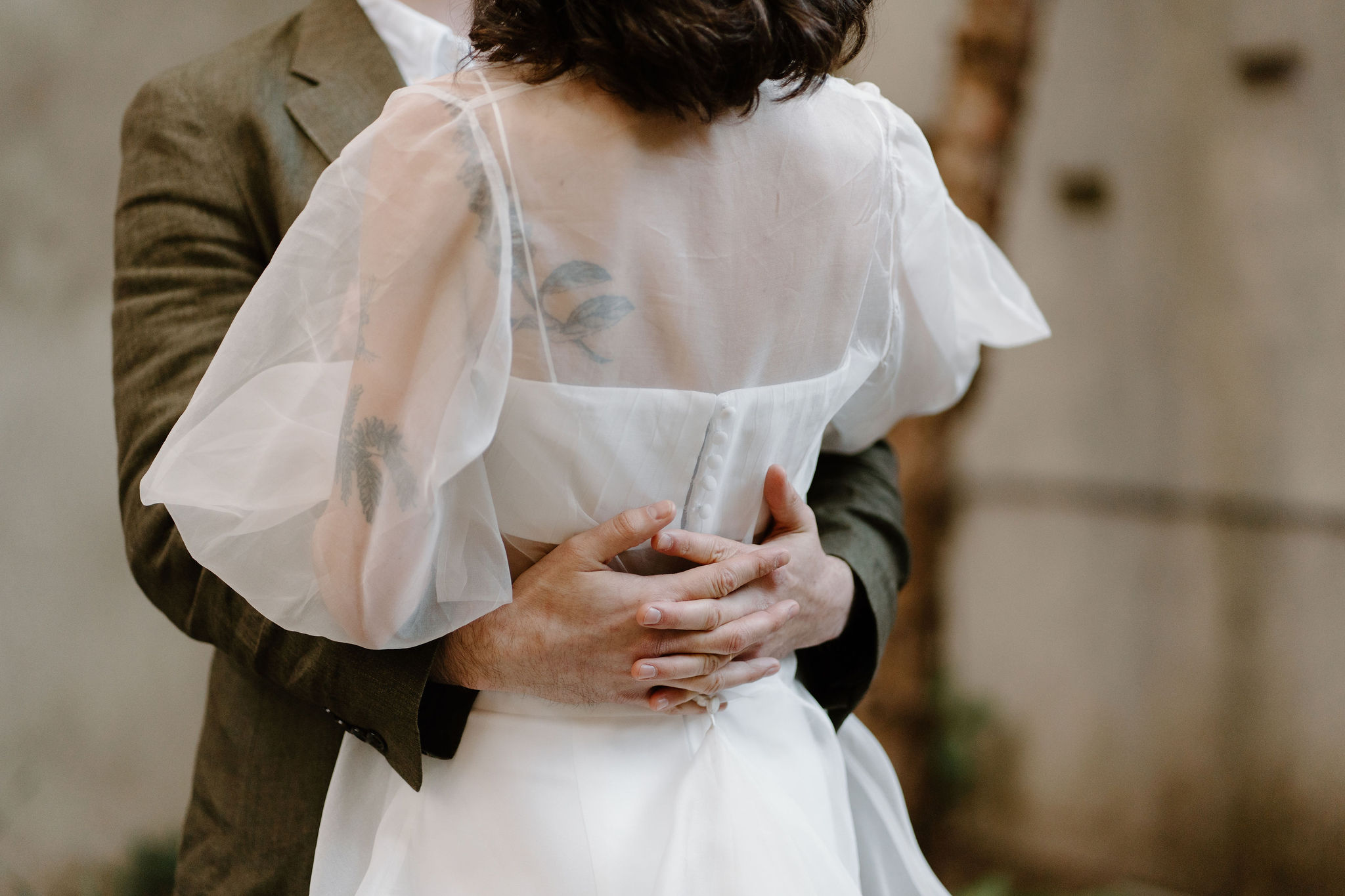 close up of groom's hands as he holds bride behind her back