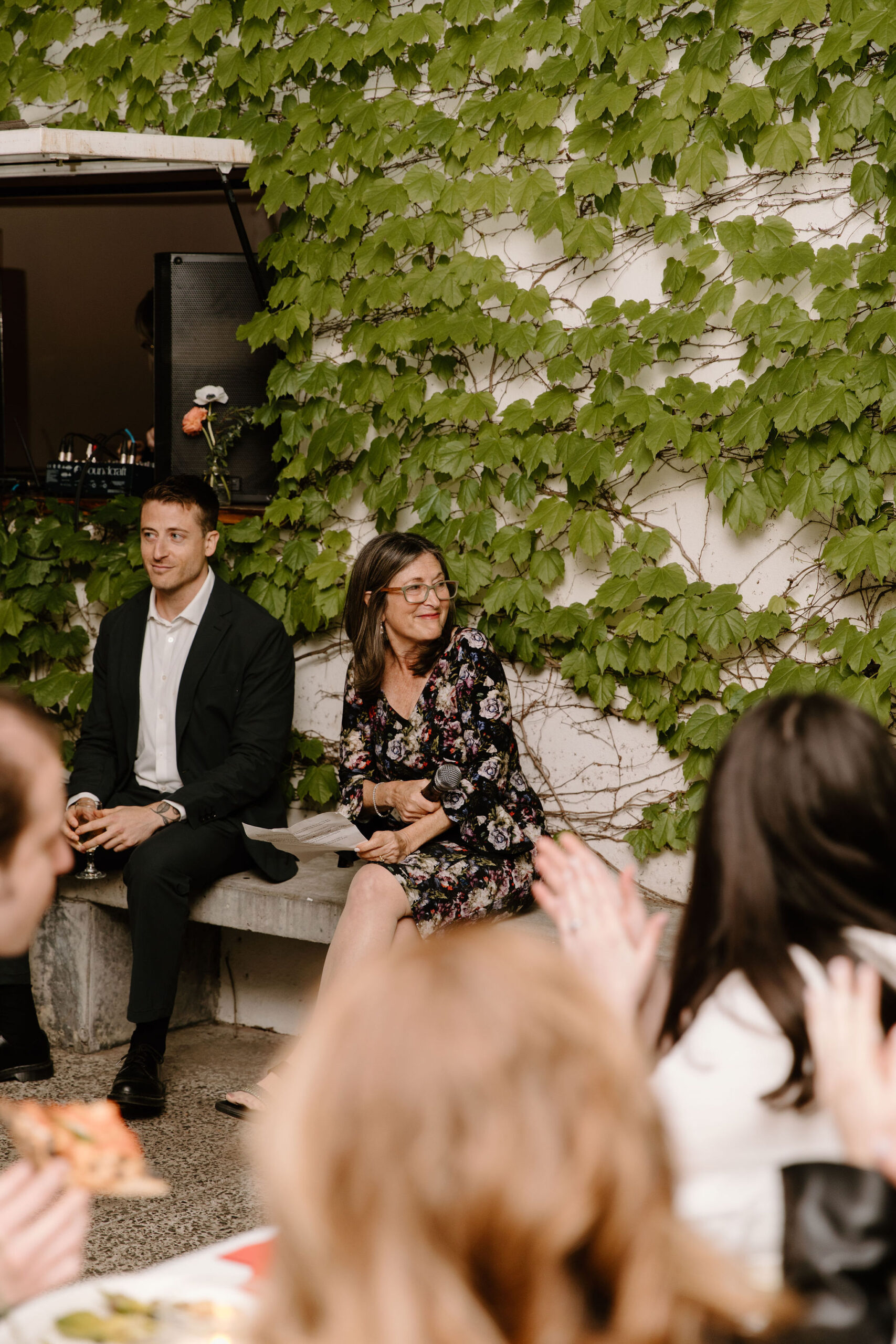 mother of the groom holding her typed speech and smiling toward bride and groom