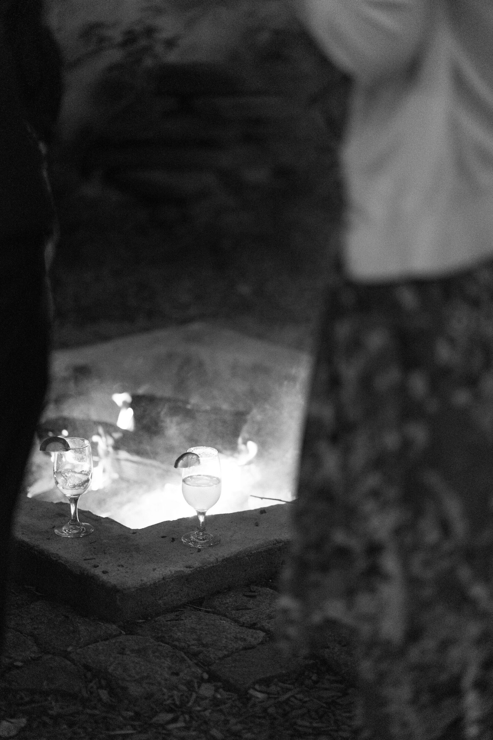 black and white image of tow cocktail glasses placed next to the fire pit