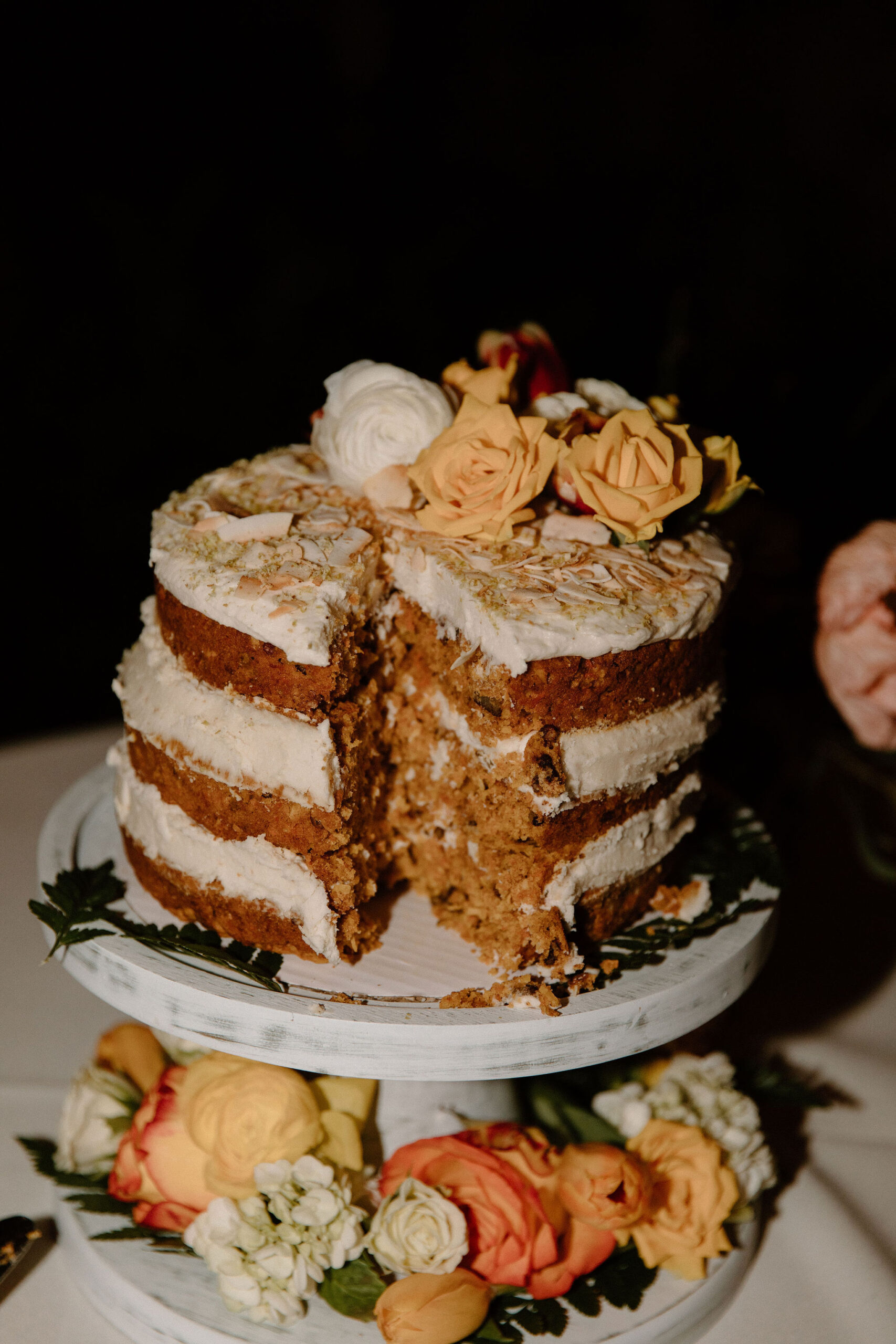 a close up of a naked carrot cake after the bride and groom had taken a slice out of it