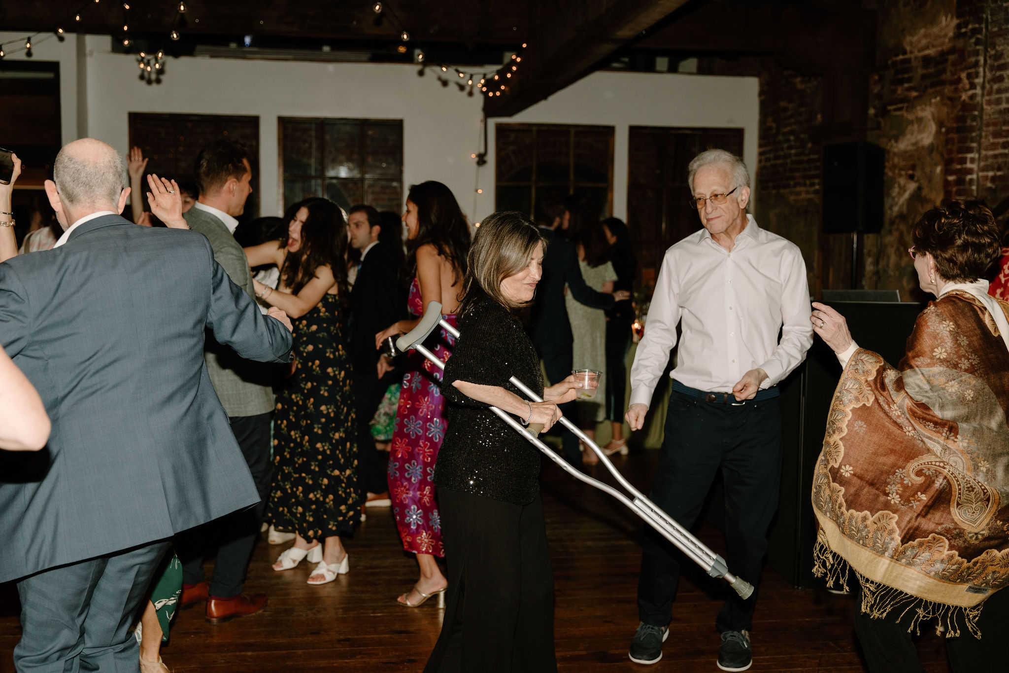 mother of the groom holding her crutch and dancing during the reception