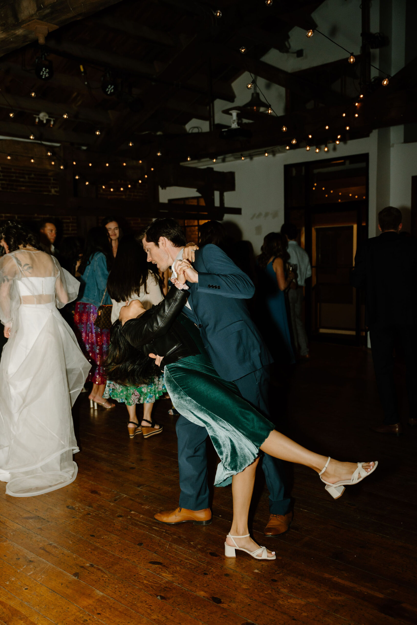 a girl in a green dress being dipped by a man in a blue suit on the dance floor