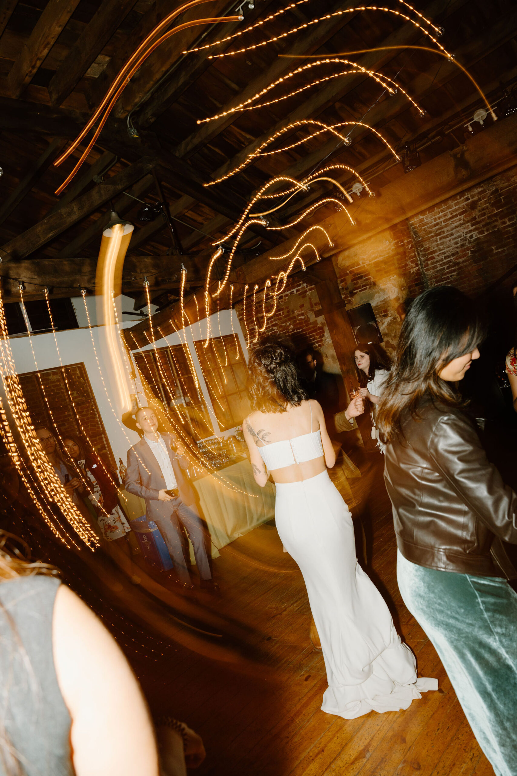 the bride, facing away from the camera, with a two piece wedding gown, surrounded by a shutter drag of lights