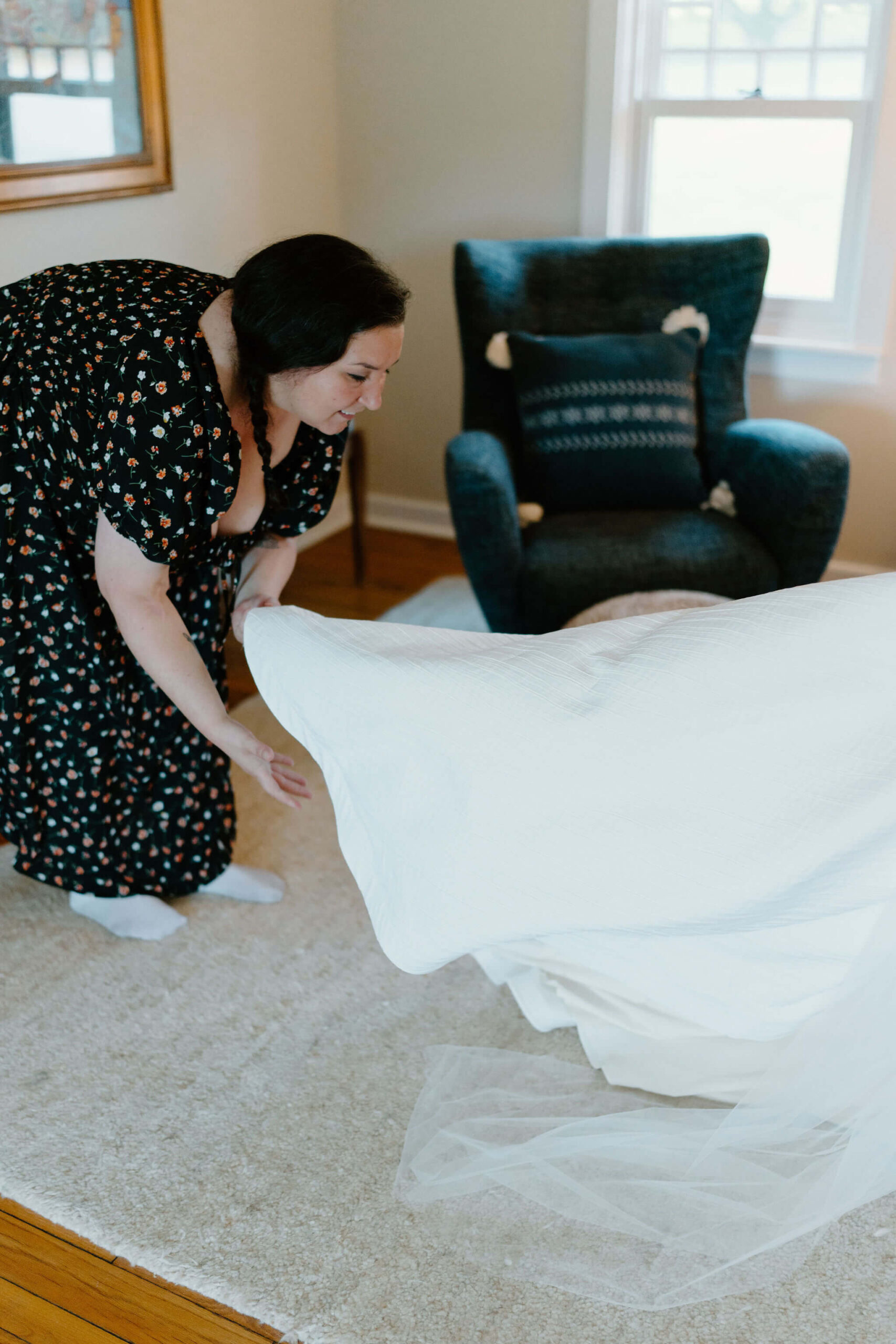 bride's friend bending over to fluff the train of her wedding gown