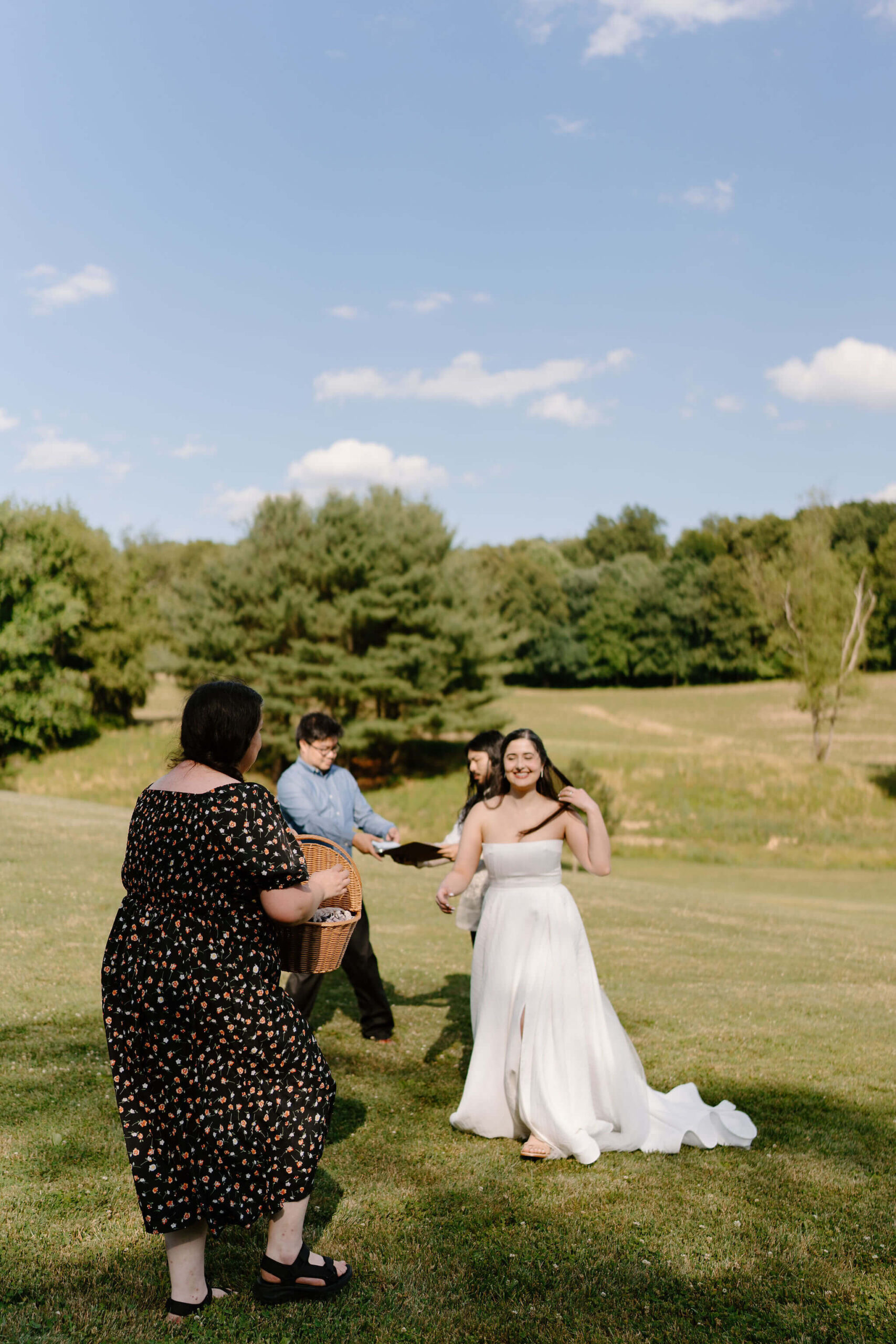 two wedding guests walking toward the couple to exchange a basket with a blanket, as well as the binder of their wedding ceremony