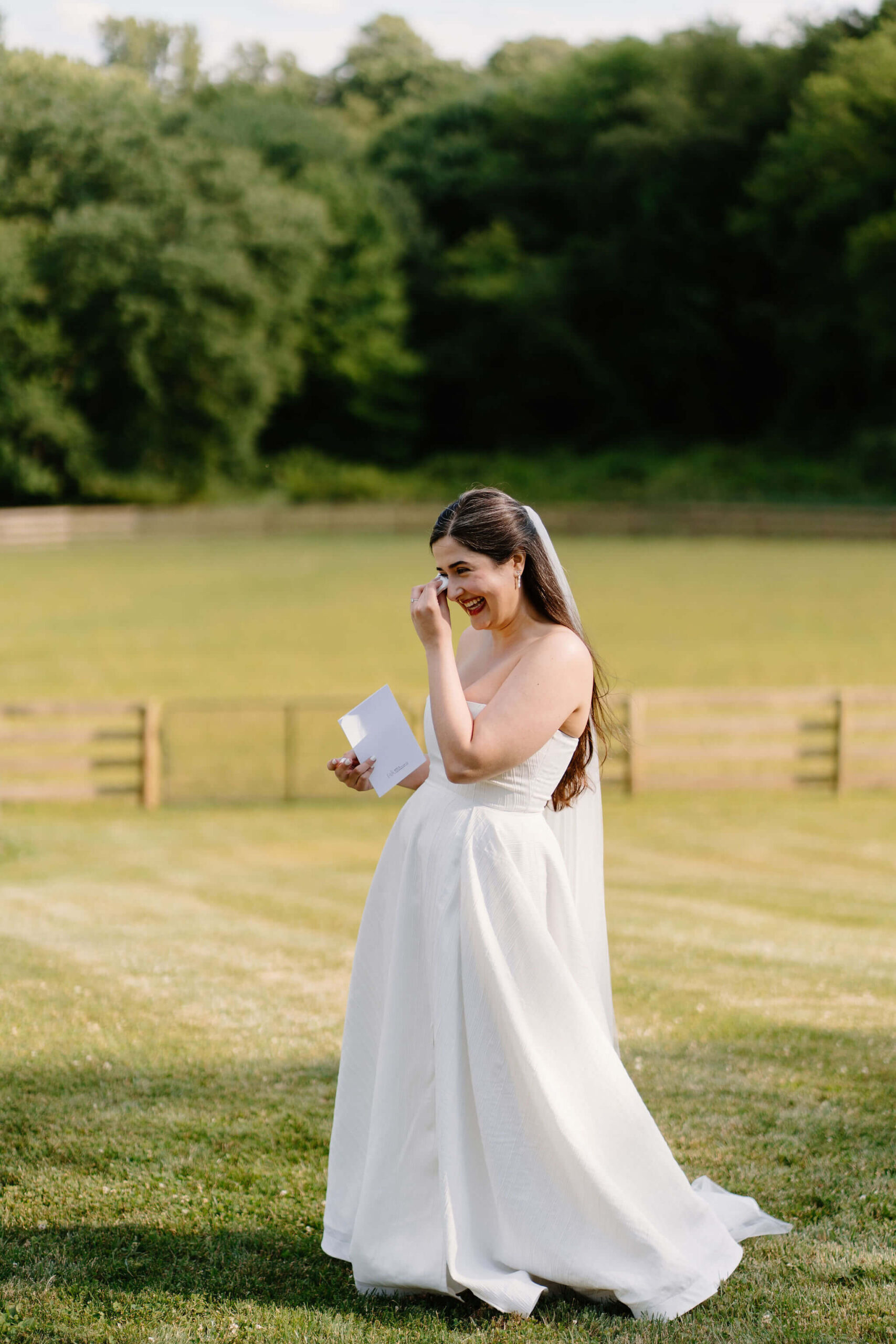 bride laughing and dabbing her teary eyes with a tissue while exchanging wedding vows