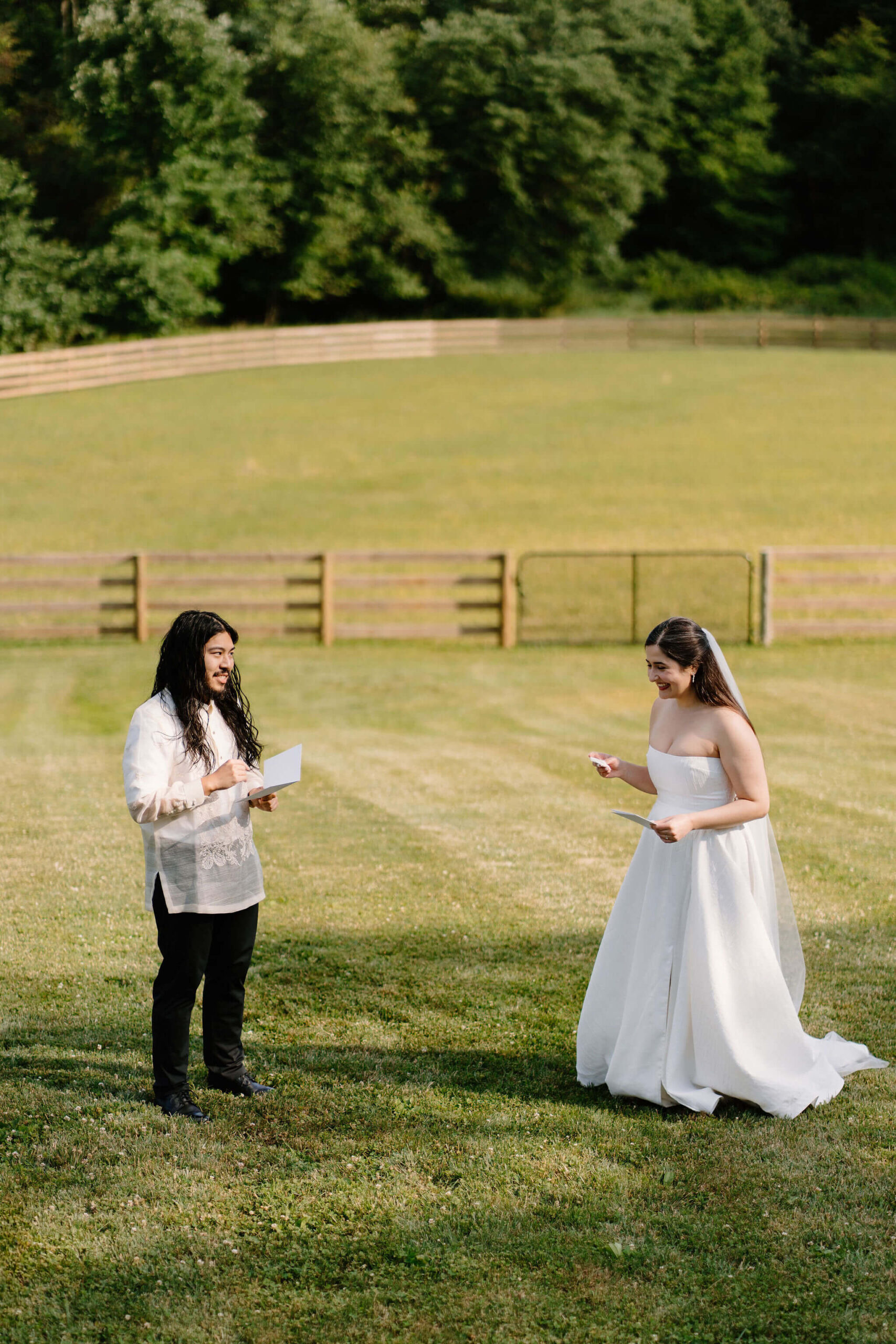 bride and groom standing in an open field on a sunny day, facing each other and exchanging vows