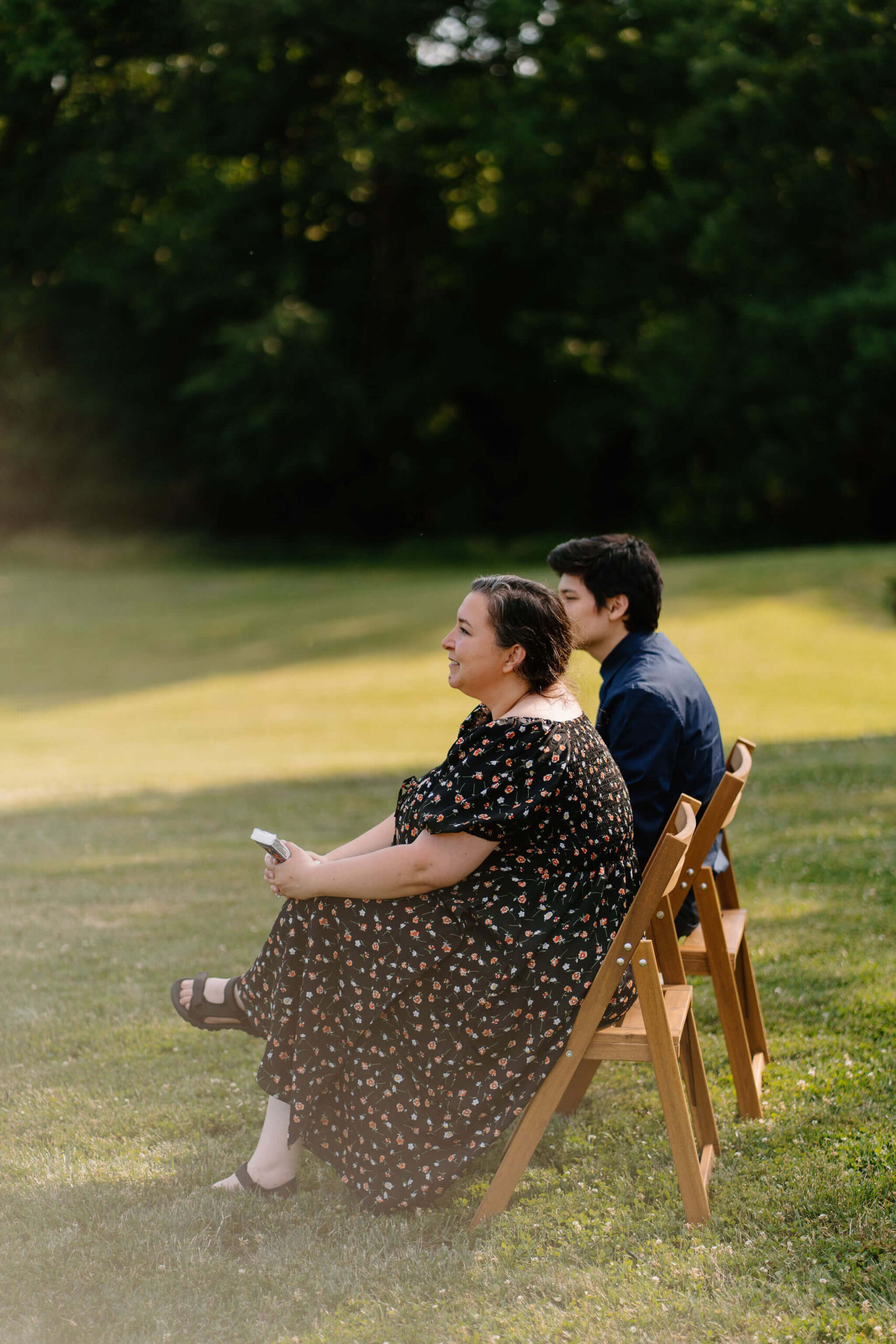 two wedding guests seated next to each other and smiling toward the bride and groom