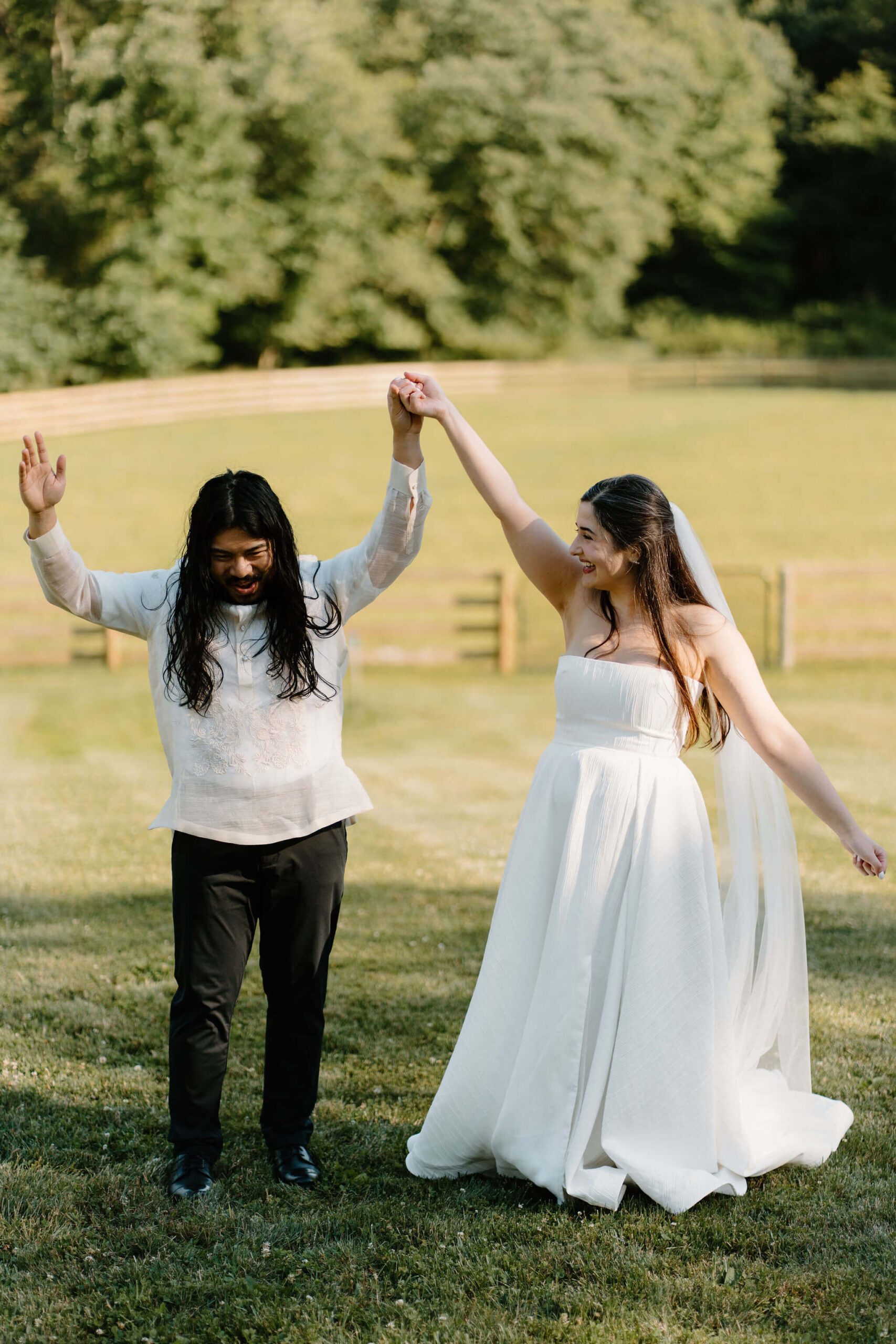 bride and groom celebrating the end of their wedding ceremony, holding hands up in the air and laughing