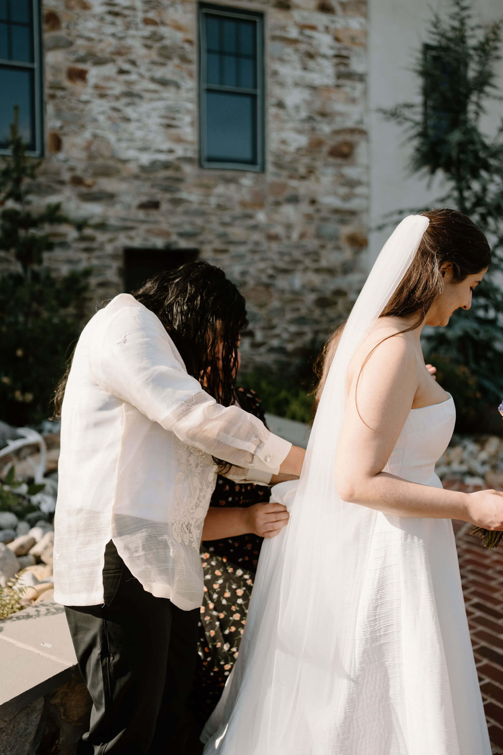 groom and friend helping bride bustle the train of her strapless white wedding gown