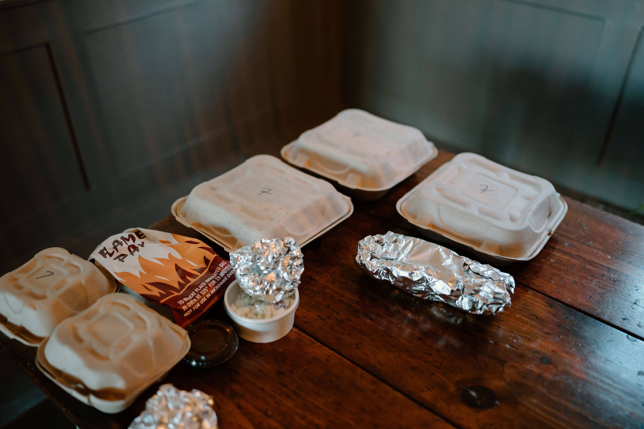 close up image of several cardboard take out containers and aluminum foil wraps