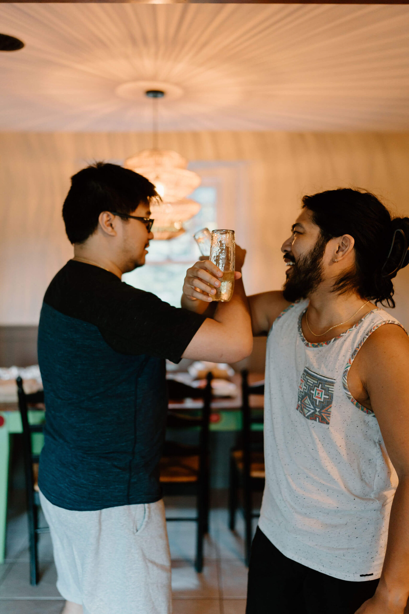 groom and his friend, wrapping their arms together at the elbows and holding champagne flutes