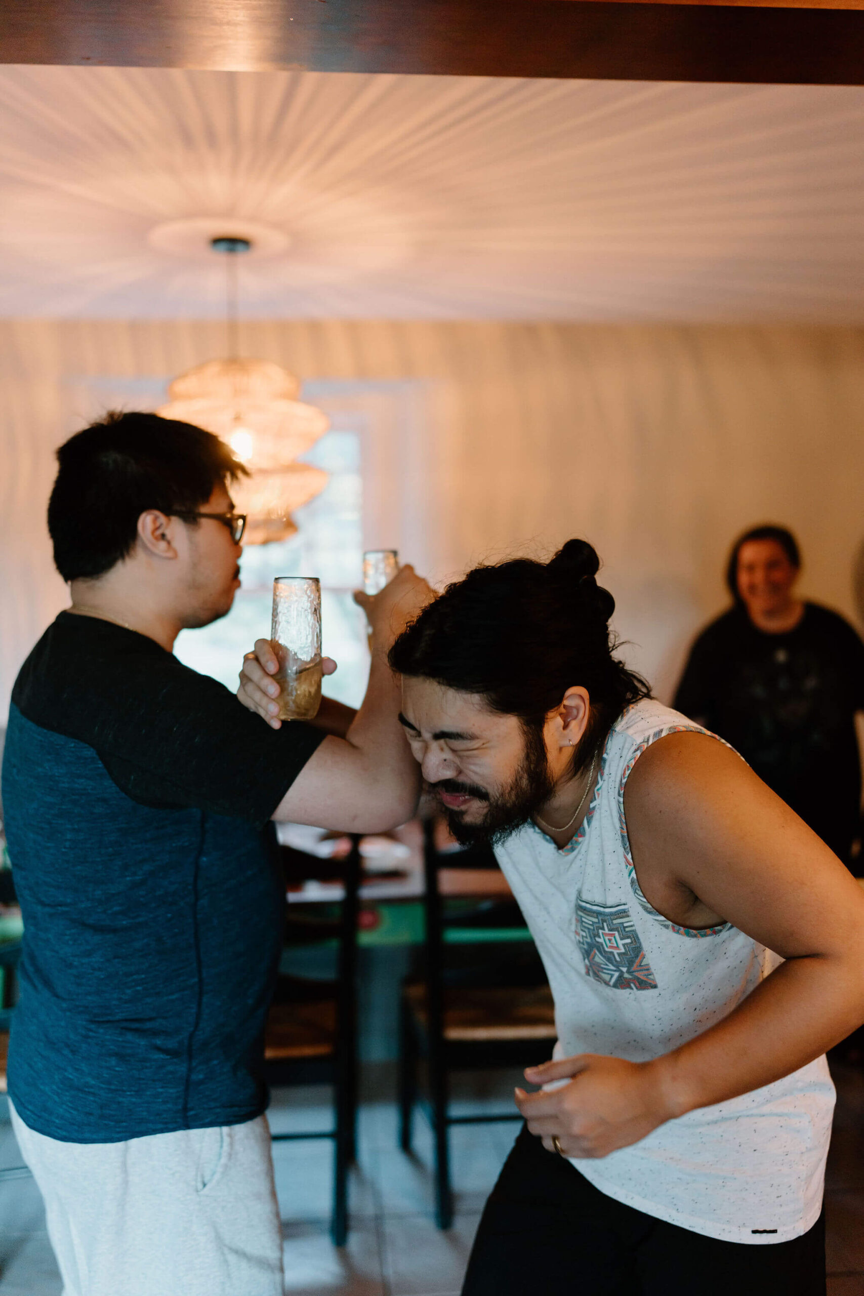 groom and his friend, wrapping their arms together at the elbows and holding champagne flutes, laughing