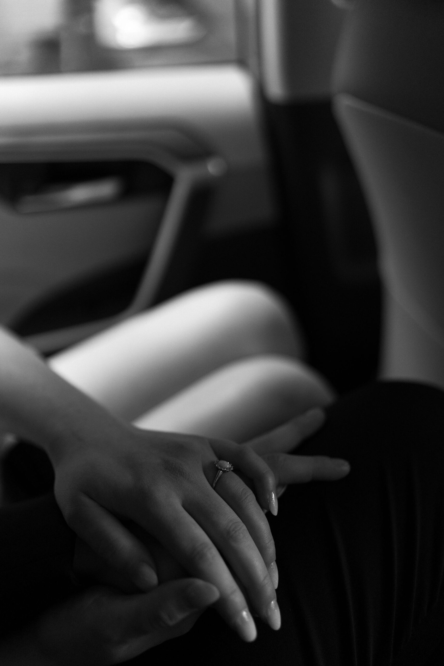 black and white close up image of bride's engagement ring as she holds the groom's hand