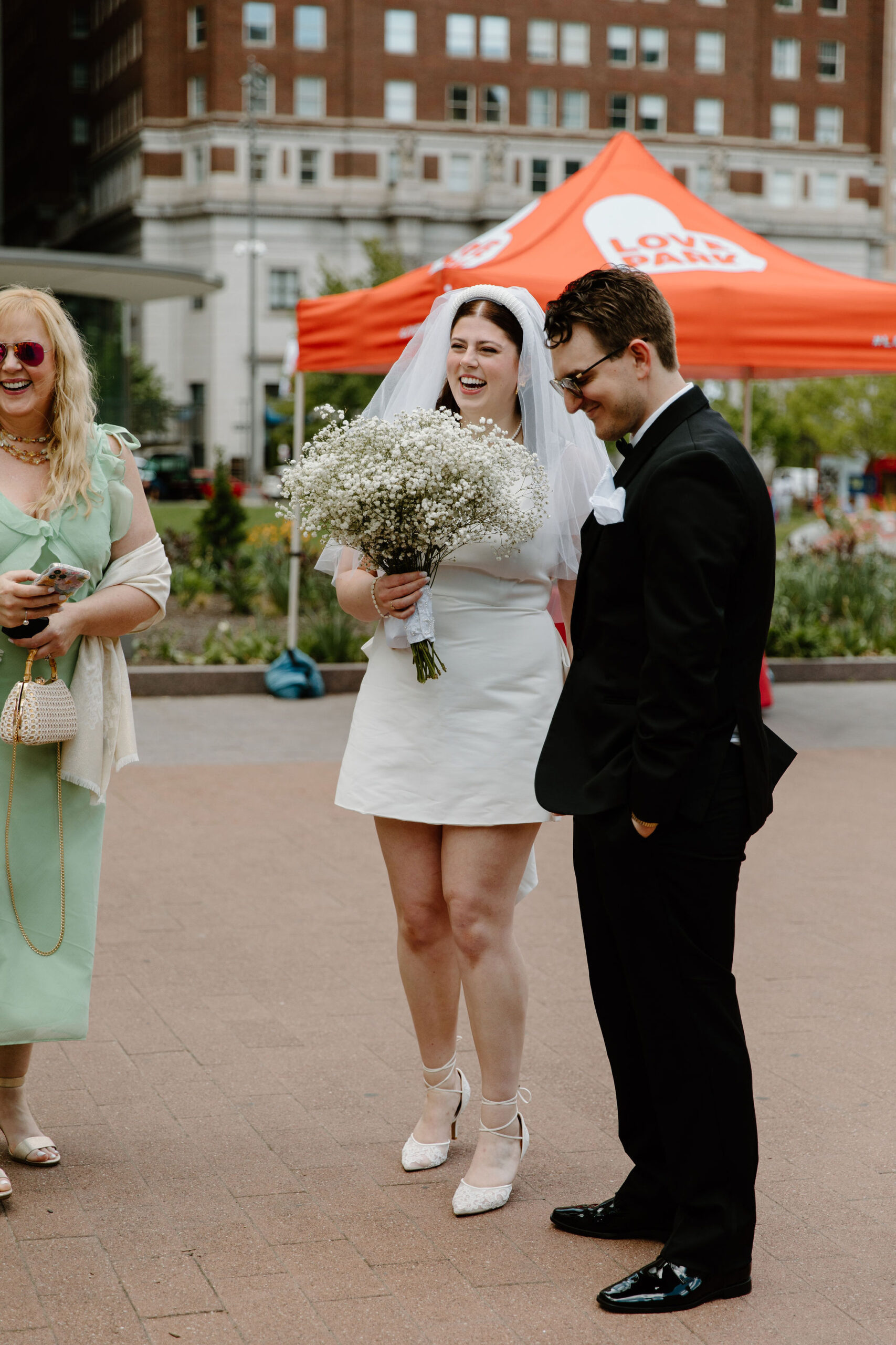 bride (holding a large baby's breath bouquet), groom, and bride's mother all laughing and talking