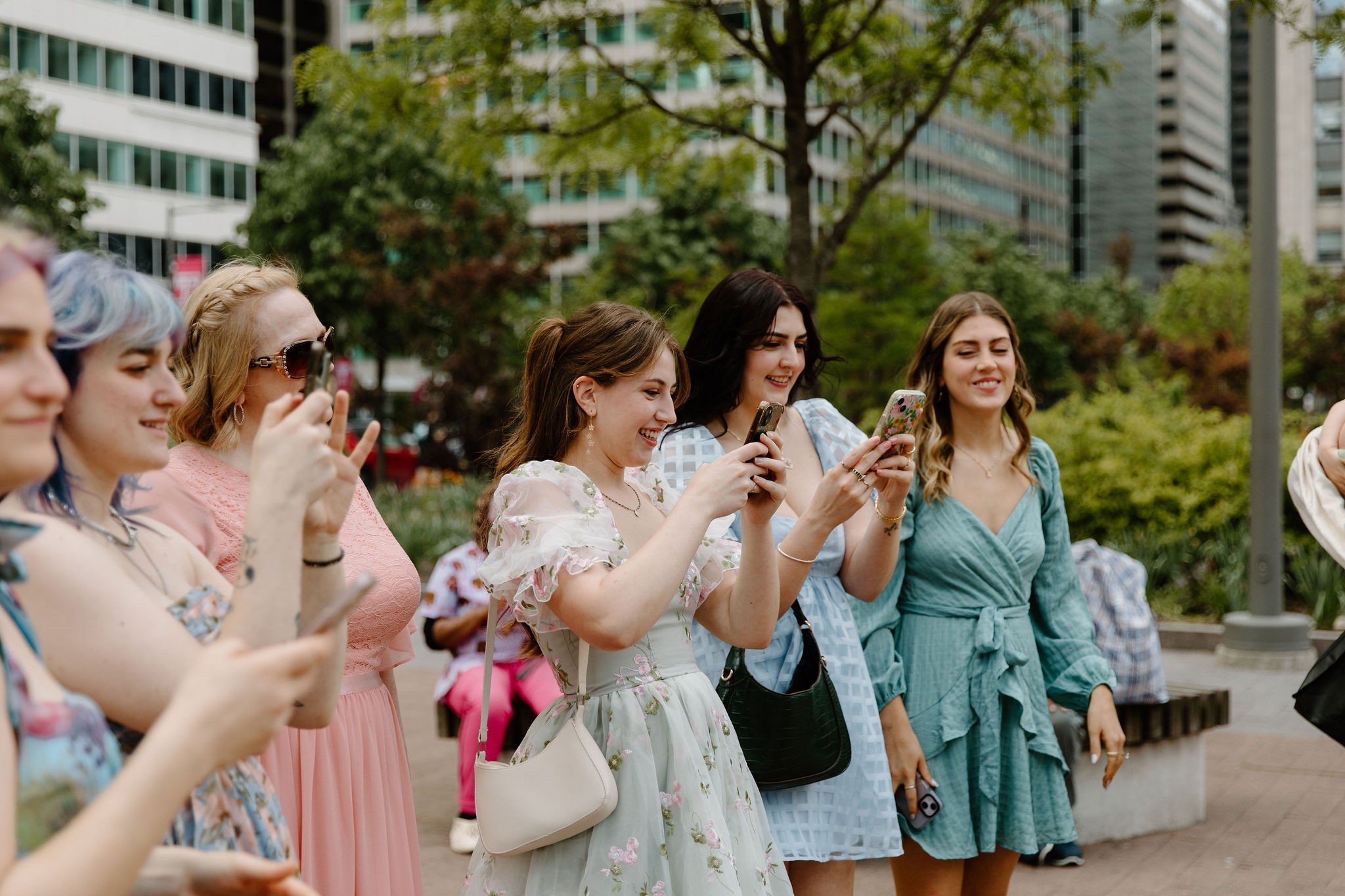 bride and groom's sisters, in colorful dresses, all on their phones to photograph bride walking down the aisle to the wedding ceremony