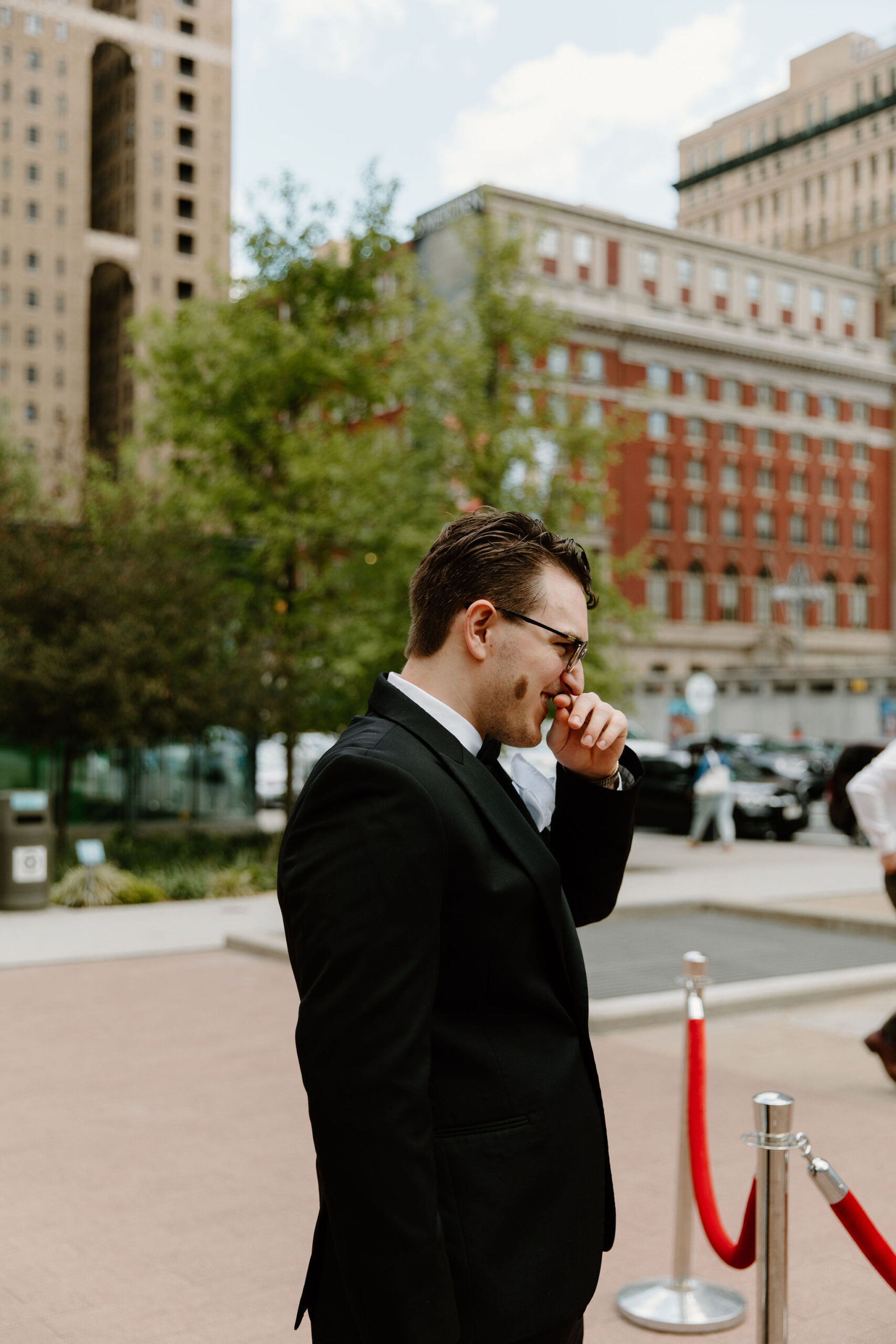 groom waiting for bride to walk down the aisle, hand to his mouth, tearing up