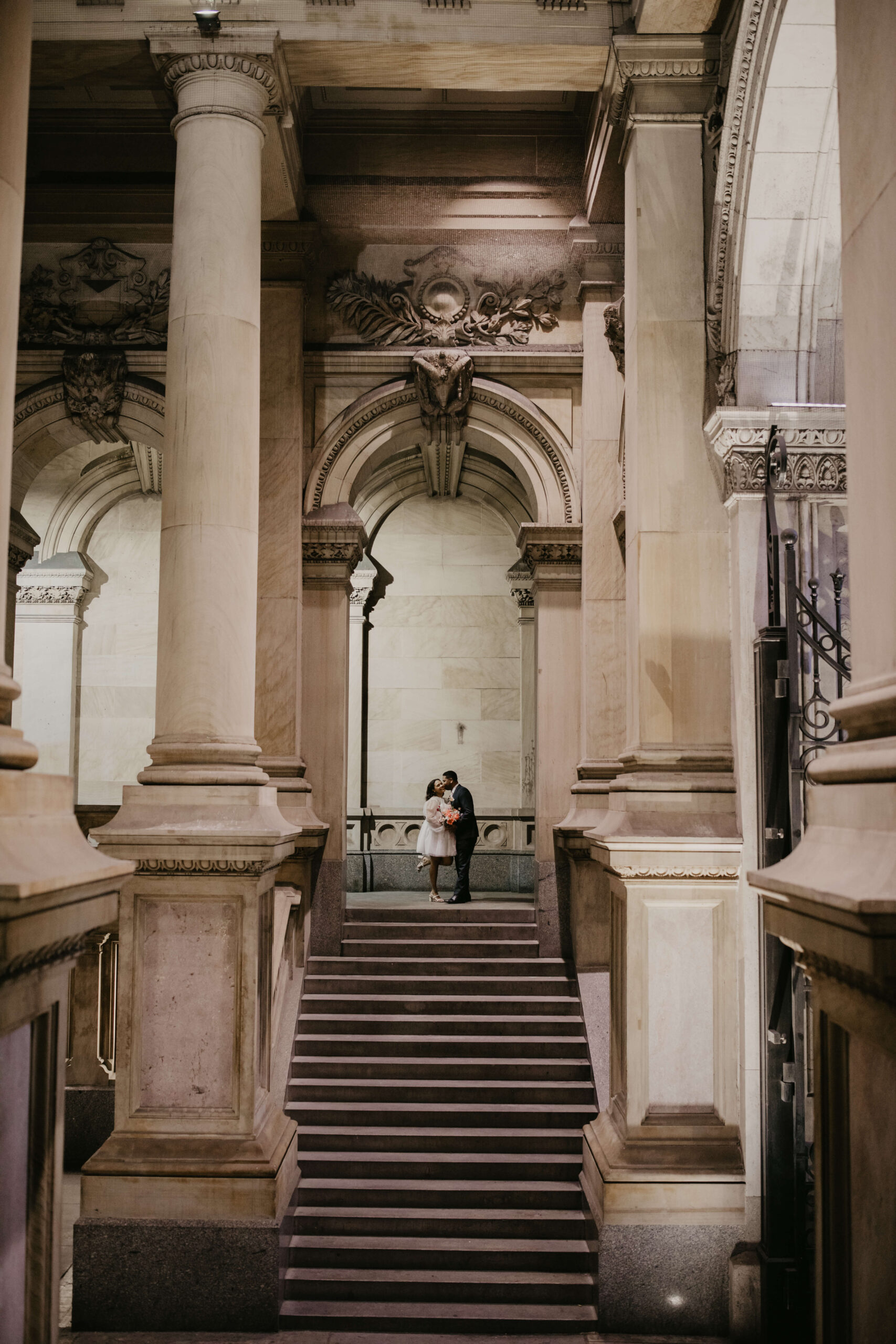 Bride and groom kissing in a stairwell at City Hall in Philadelphia