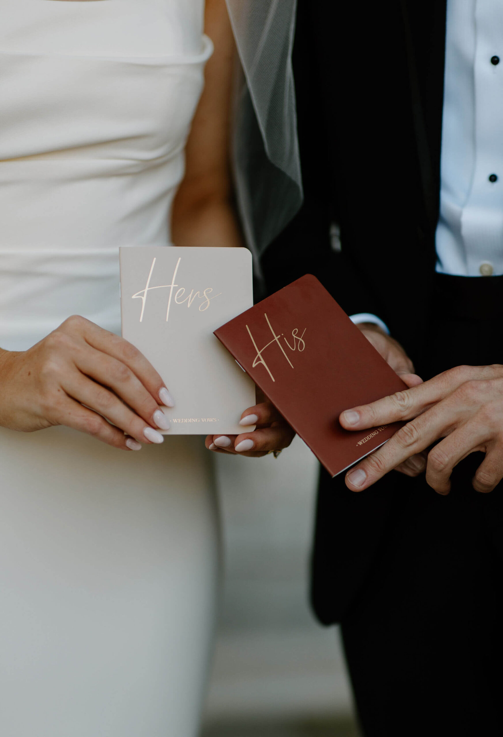 Close up image of bride and groom each holding their own personalized vow books