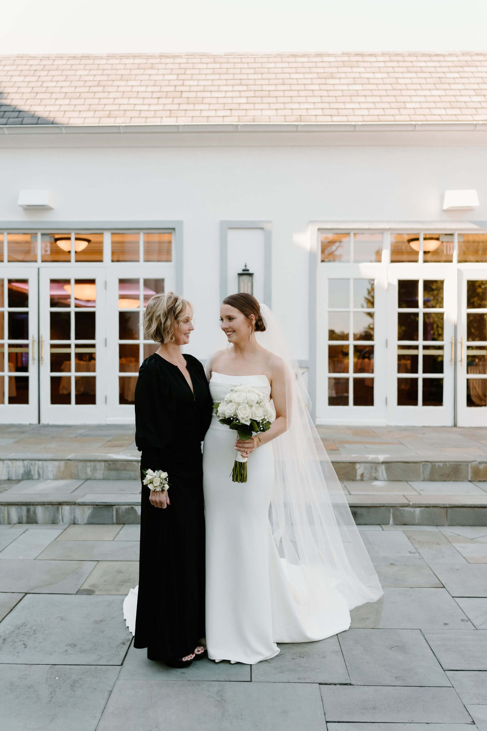 bride and her mother (long sleeve black dress) smiling at each other